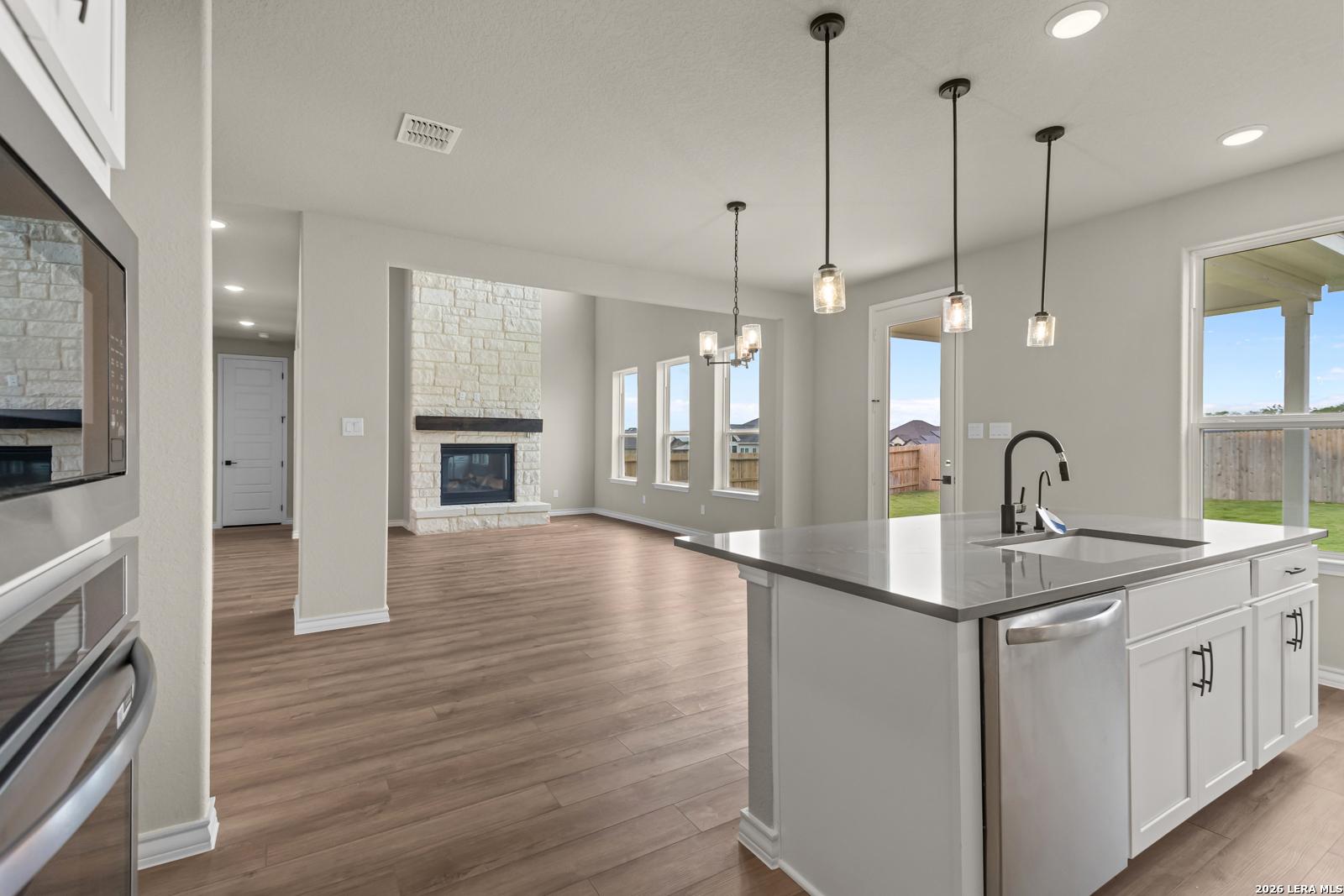 Open-concept kitchen and living area with stone fireplace in The Danbury H floor plan at The Reserve at Potranco Oaks.