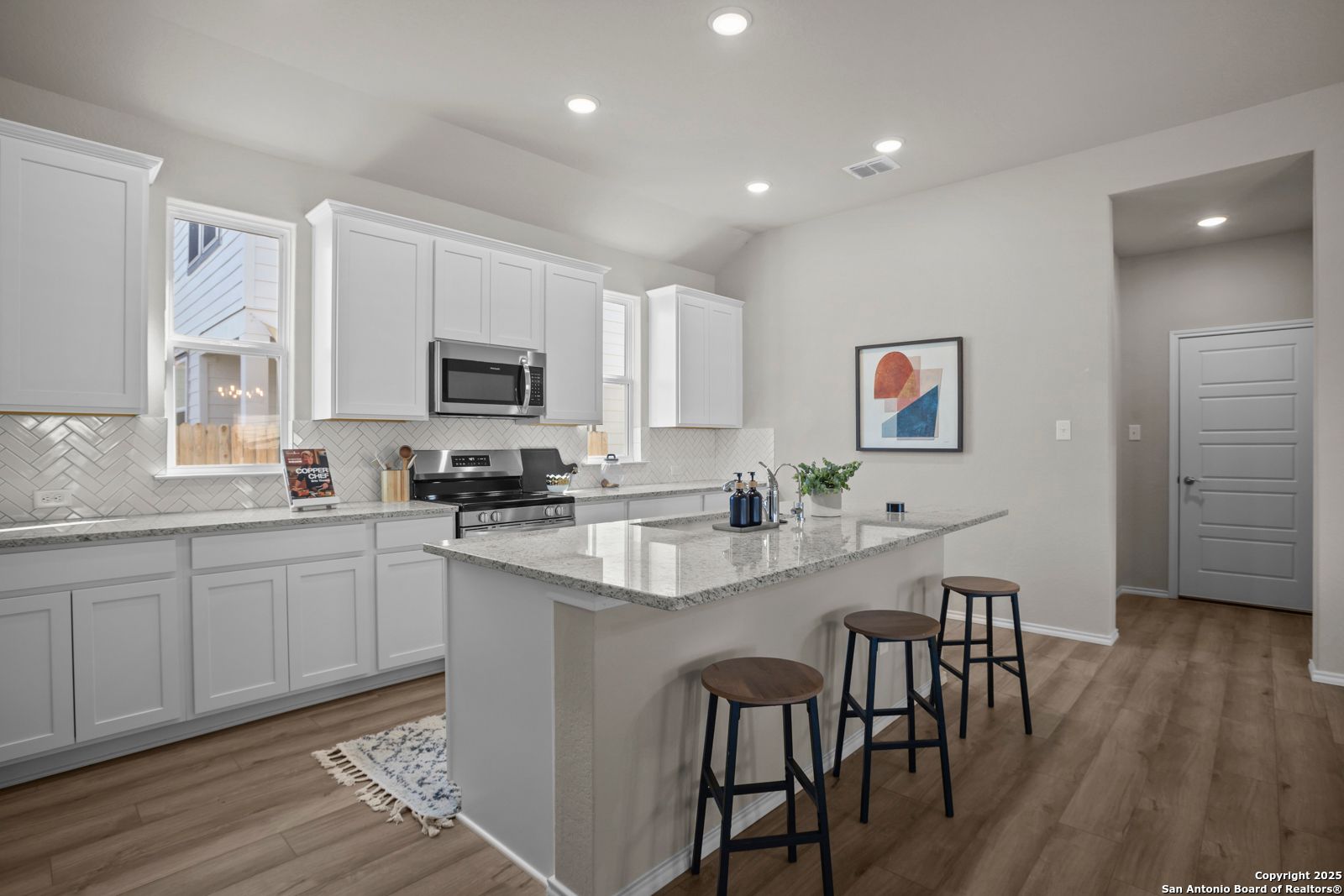 Modern white kitchen with granite island, stainless appliances, subway tile backsplash in Davidson Homes The Collin B, Seguin TX