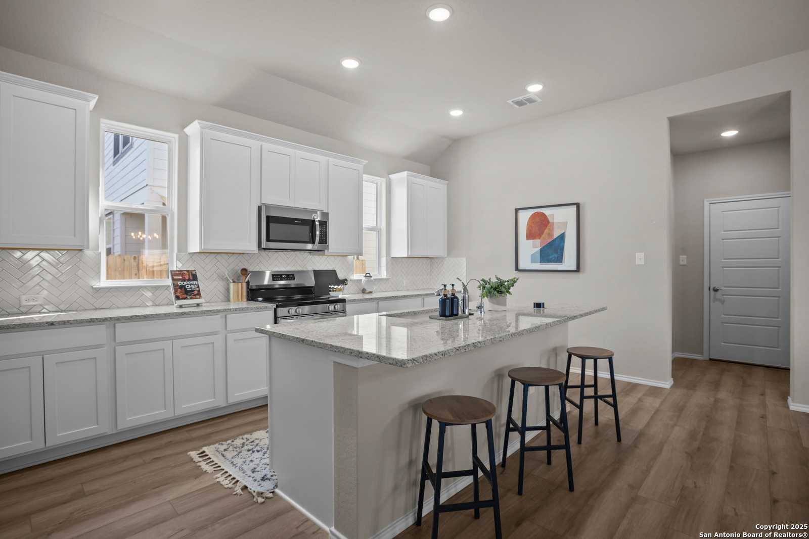 Modern white kitchen with granite island, stainless appliances, subway tile backsplash in Davidson Homes The Collin B, Seguin TX