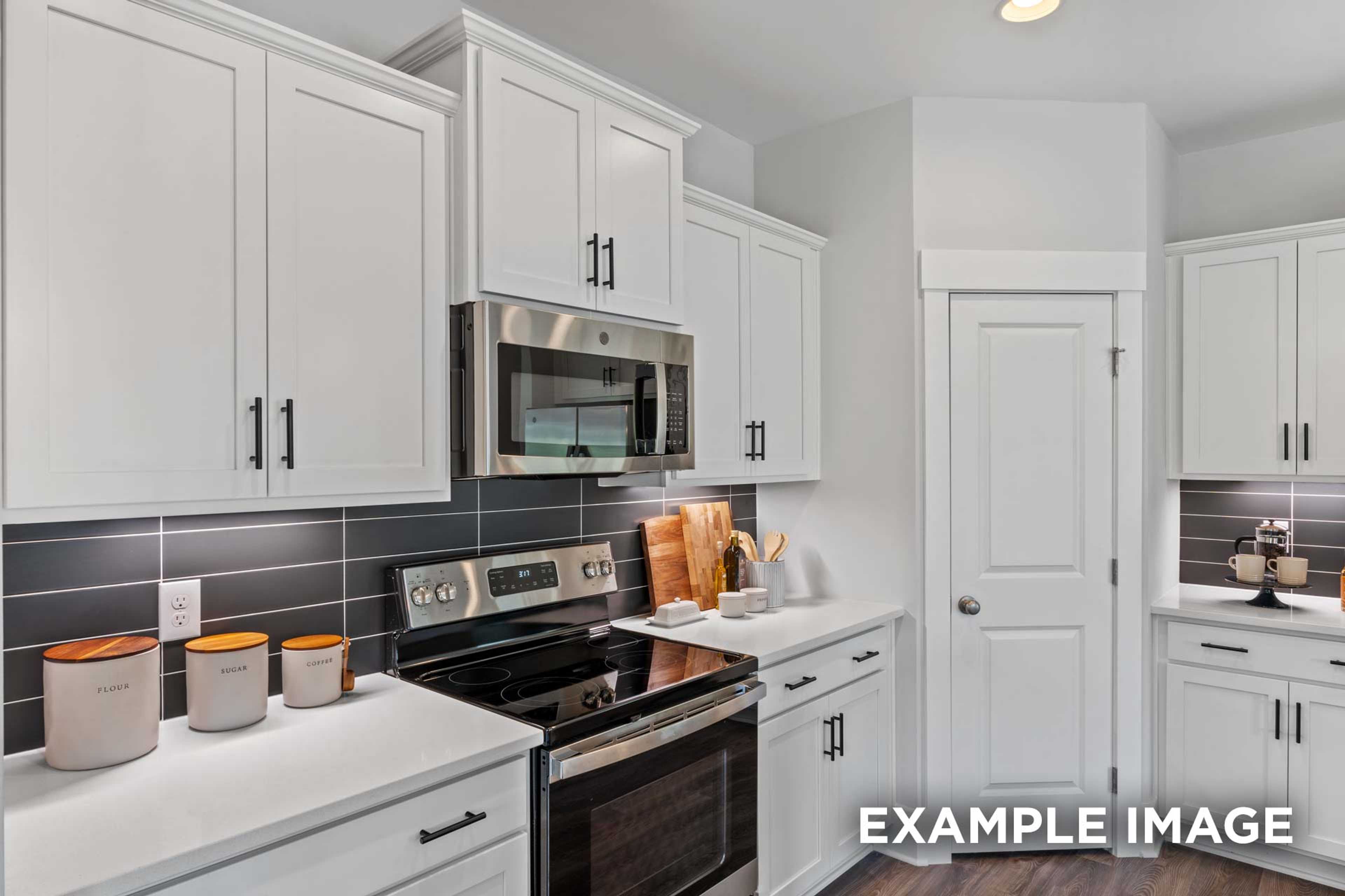 Spacious kitchen in The Franklin C with white shaker cabinets, stainless steel appliances, gray subway tile backsplash