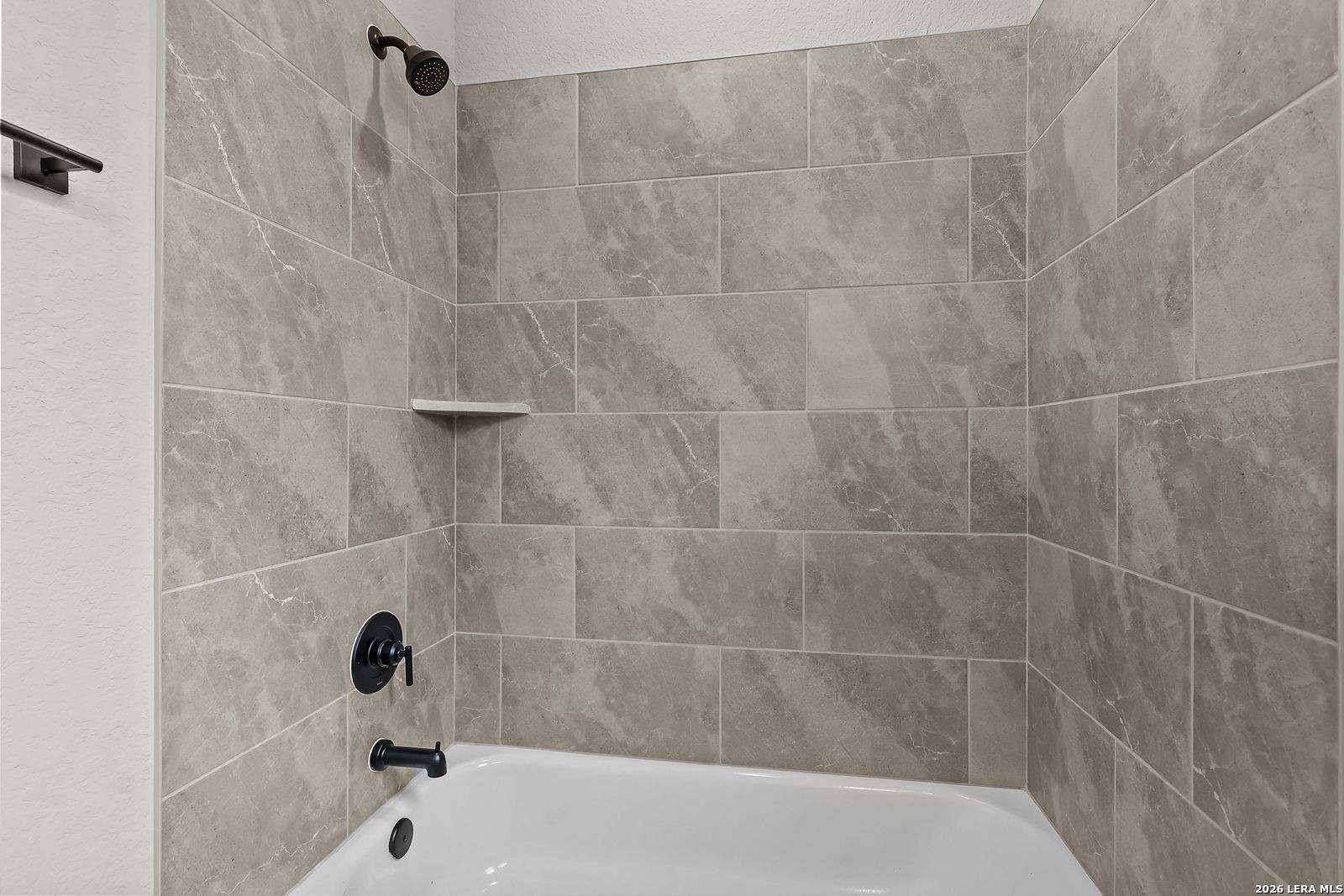 Modern gray marble tile shower and soaking tub with black fixtures in Davidson Homes The Belmont H, Castroville, Texas