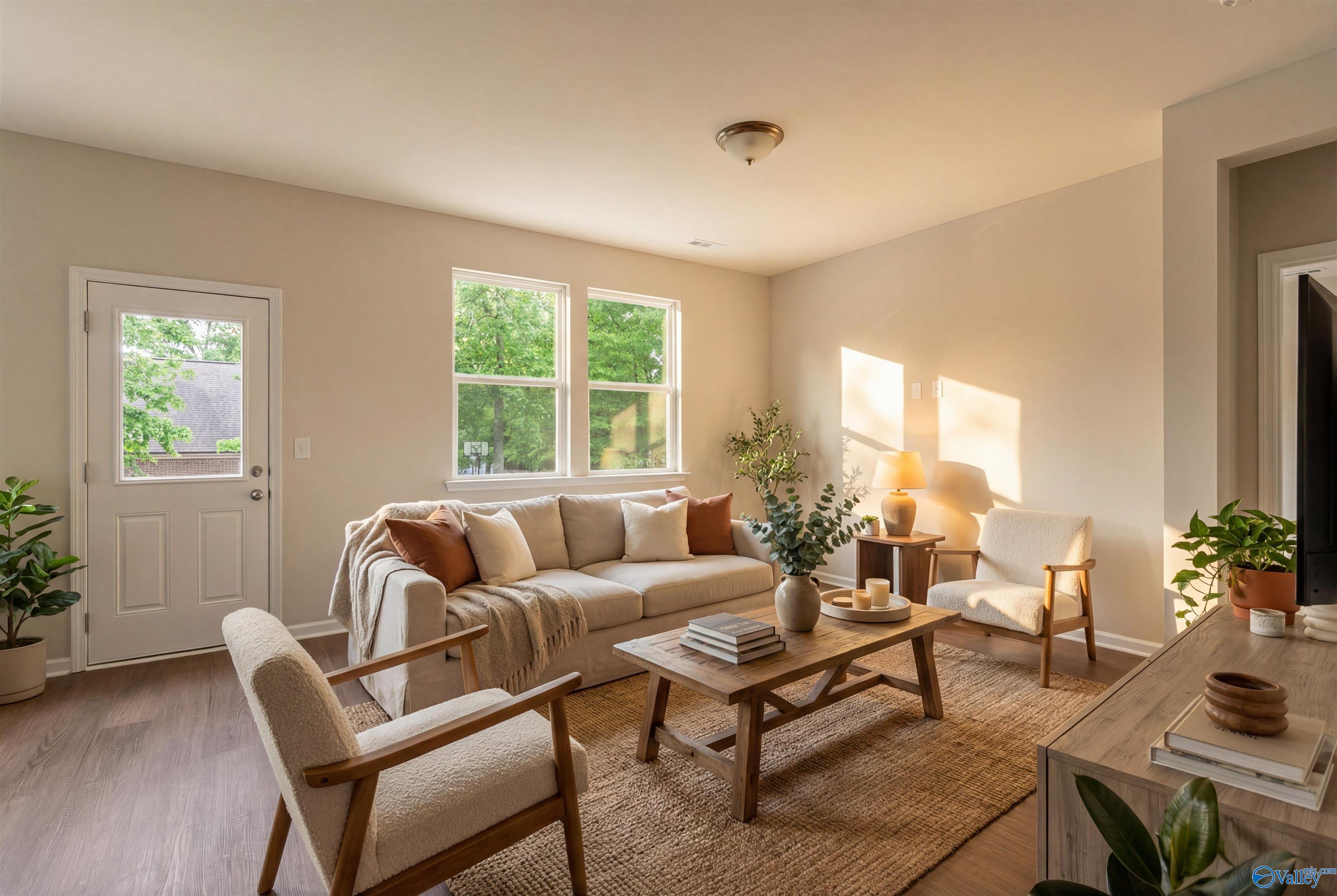 Cozy living room with beige sofa, wooden coffee table, armchairs, plants, and natural light in Davidson Homes The Phoenix, Fayetteville, TN