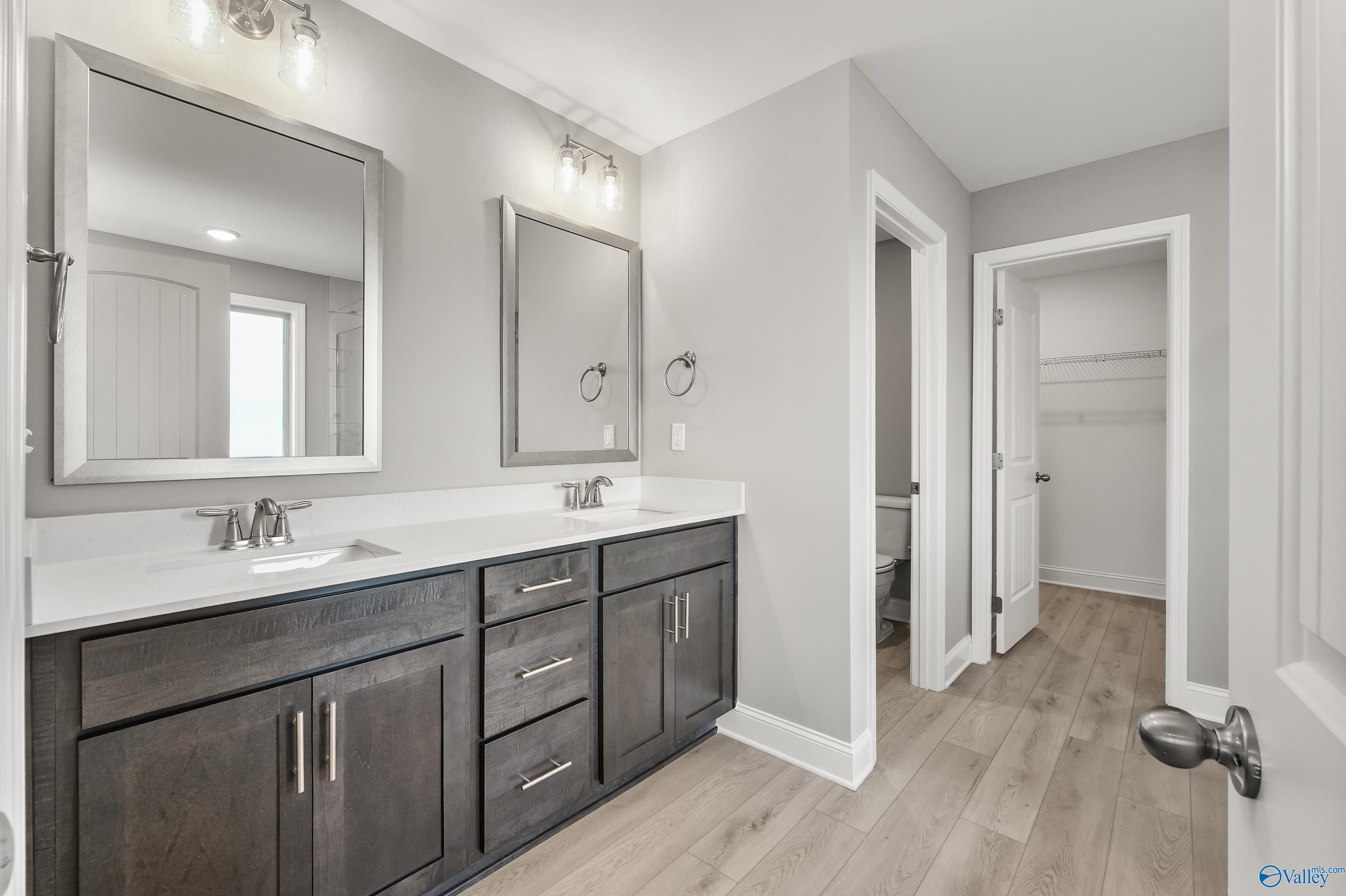 Modern master bathroom featuring double vanity with gray shaker cabinets, quartz counters, and adjacent closet in Davidson Homes The Everett B, Athens, Alabama