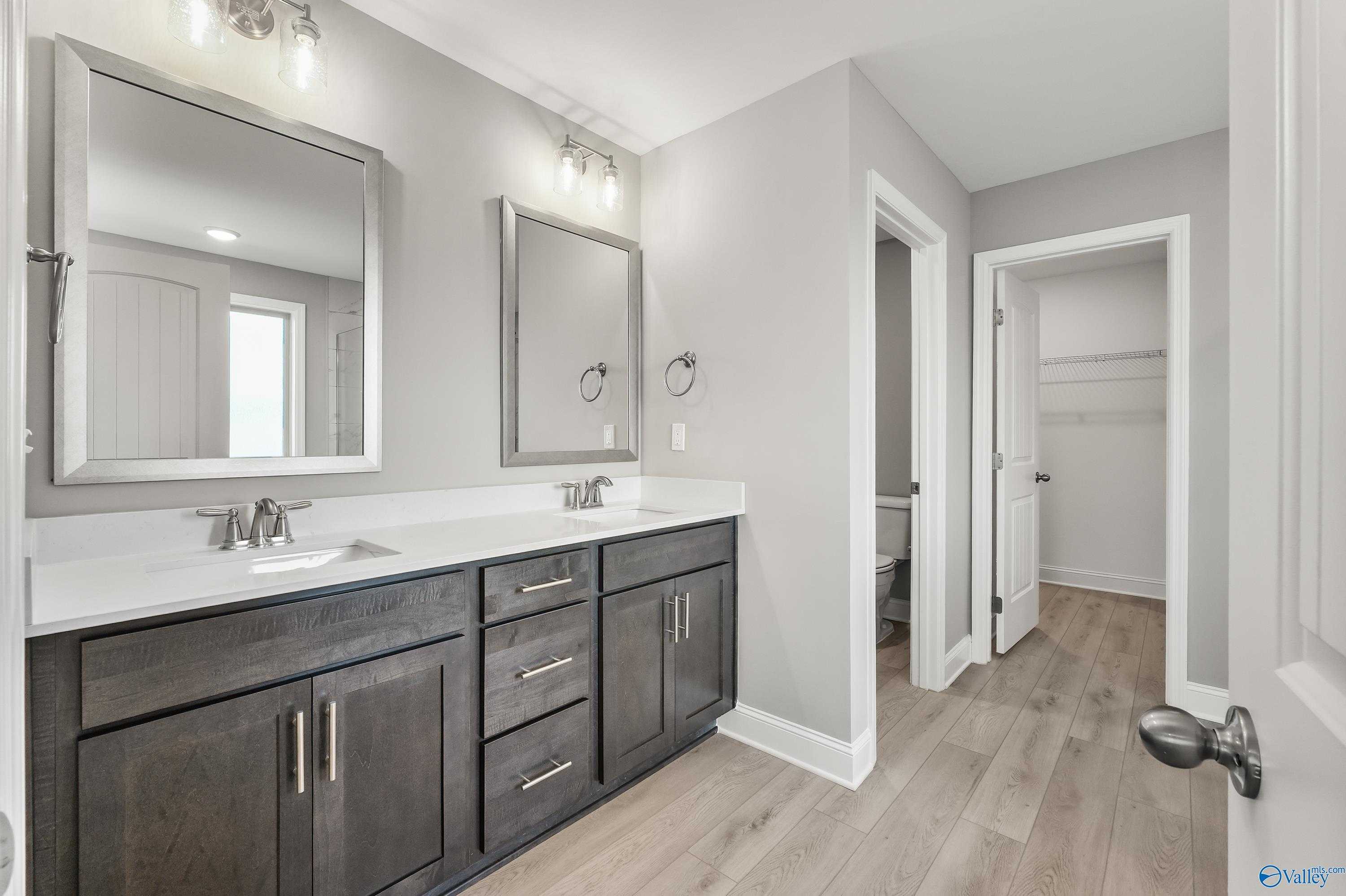 Modern master bathroom featuring double vanity with dark cabinets, quartz counters, and mirrors in Davidson Homes The Everett B, Athens, Alabama