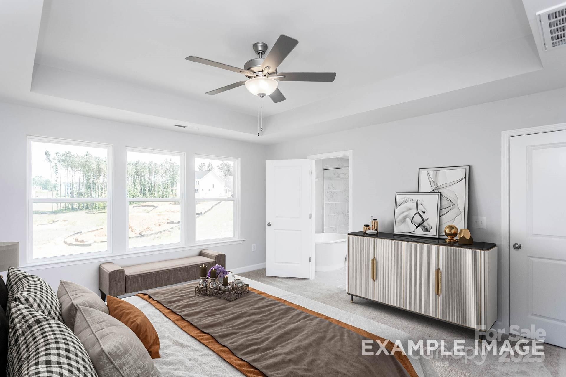 Elegant master bedroom with ceiling fan, large windows, bench seating, and en-suite bath in Davidson Homes The Hemlock A, Belmont, NC