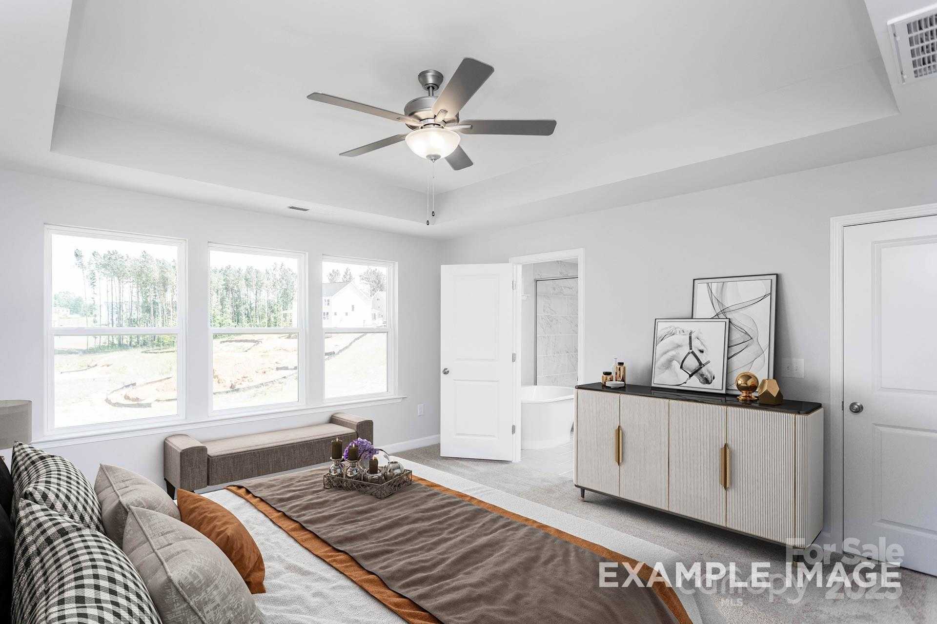 Cozy master bedroom with plush bed, neutral tones, en-suite bath, and wooded views in Davidson Homes The Hemlock A, Belmont, NC