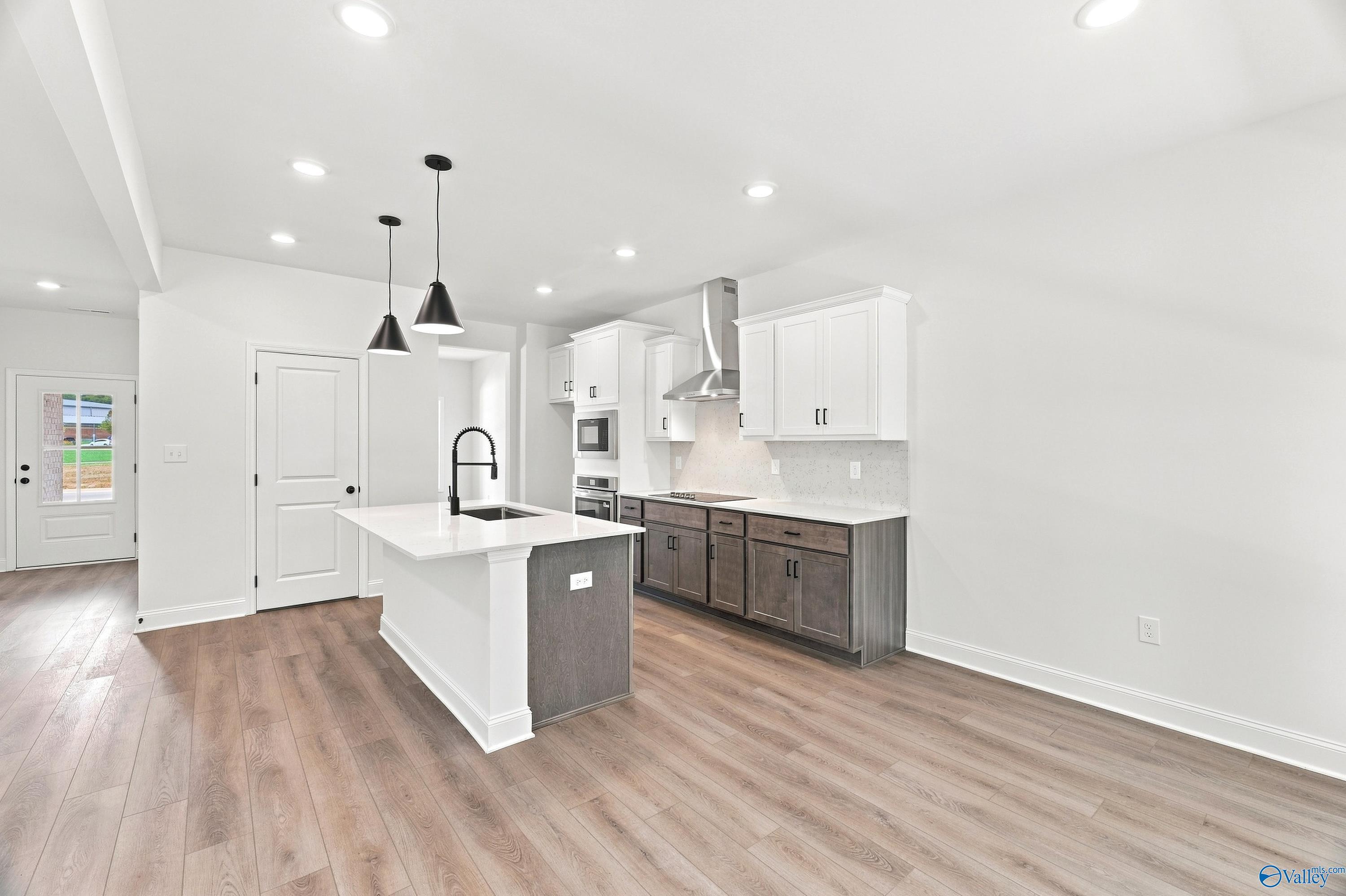 Modern kitchen with two-tone cabinetry, quartz island, and pendant lighting in The Shelby B plan at Jaguar Hills, Huntsville.