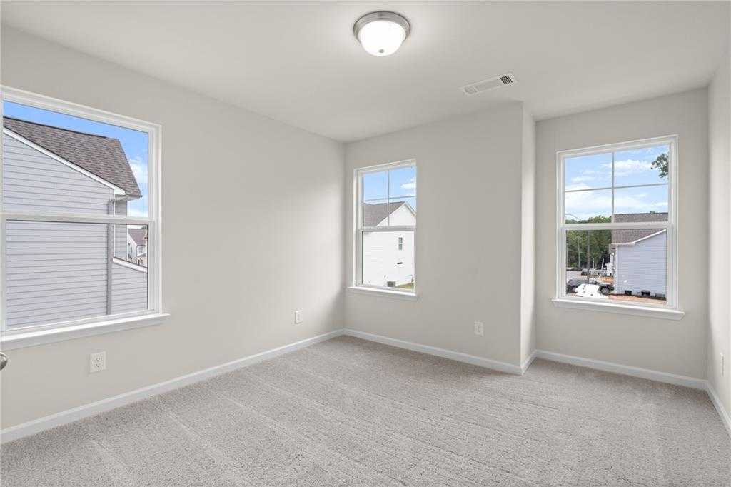 Bright secondary bedroom with light gray walls, beige carpet, large windows overlooking neighborhood in The Marion B, Kennesaw, Georgia