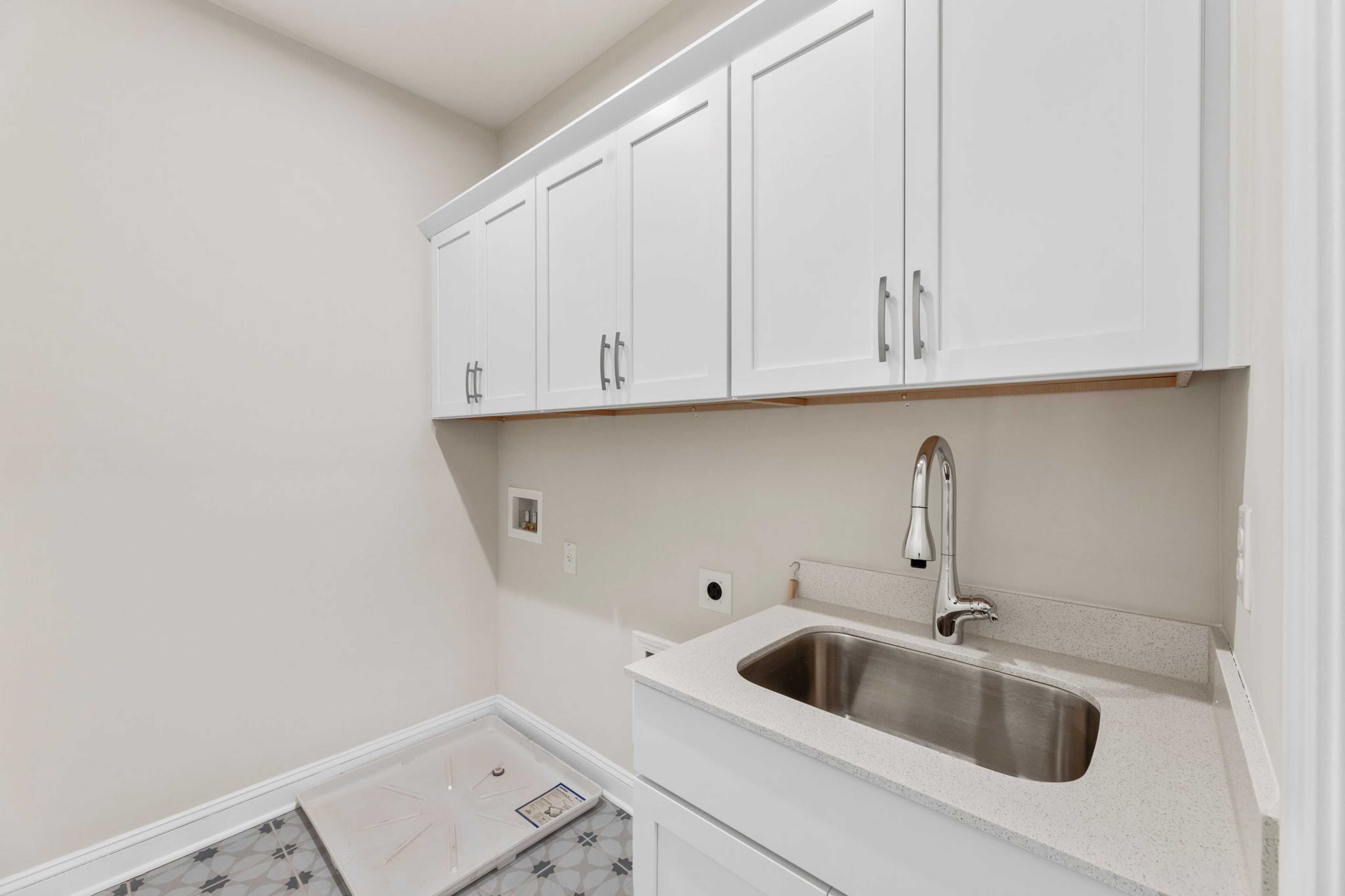 Modern laundry room in Melody Lakeside Estates, Buford GA with white shaker cabinets, stainless sink, and utility hookups