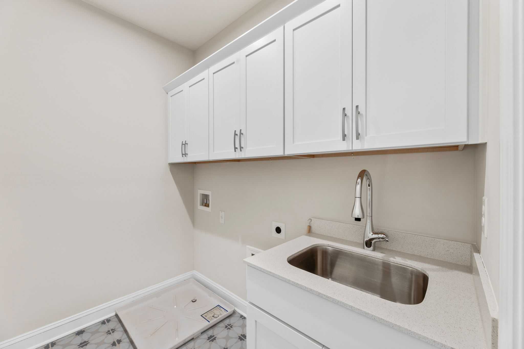 Modern laundry room in Melody Lakeside Estates, Buford GA with white shaker cabinets, stainless sink, and utility hookups