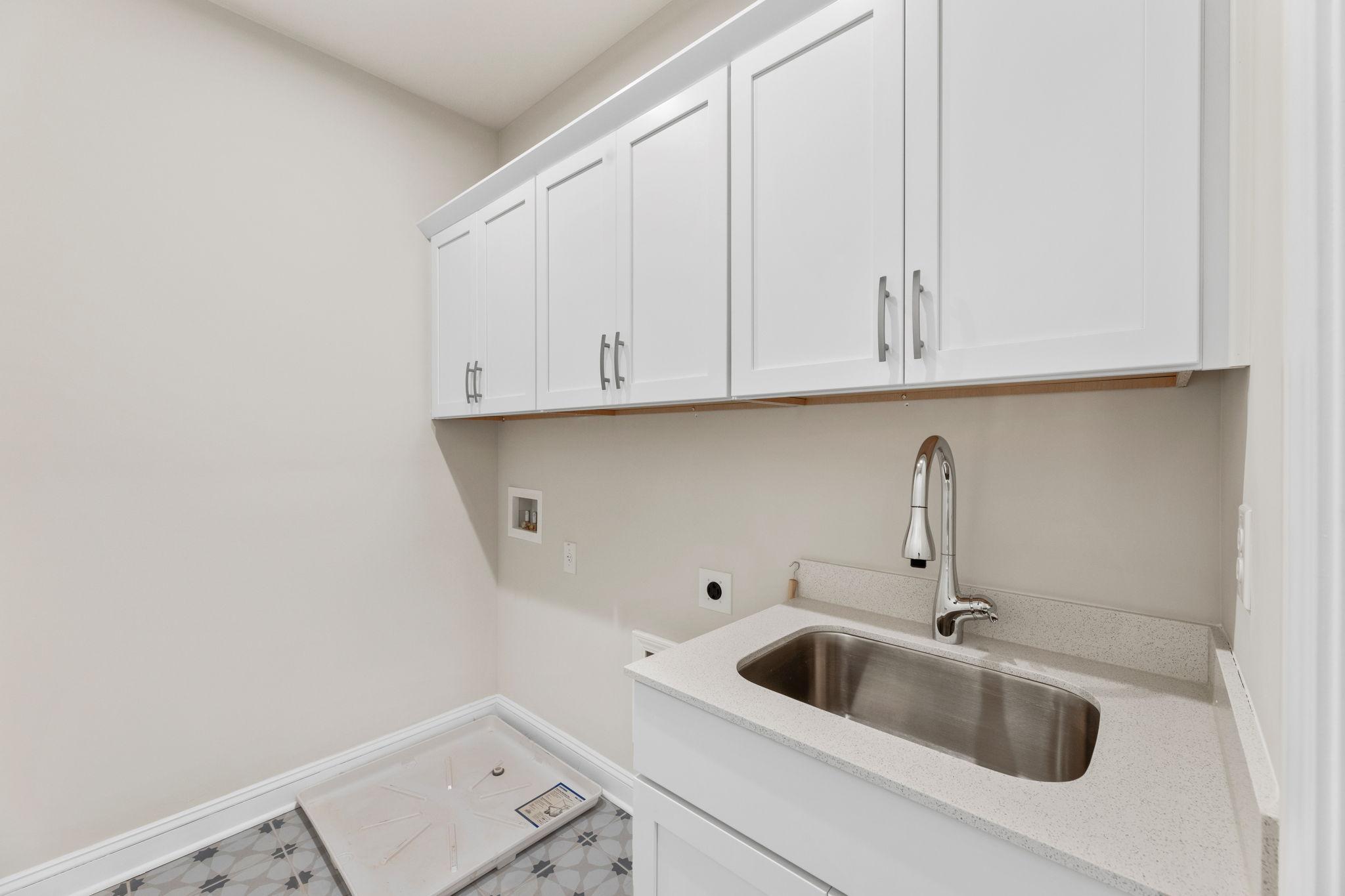 Modern laundry room in Melody Lakeside Estates, Buford GA with white shaker cabinets, stainless sink, and utility hookups