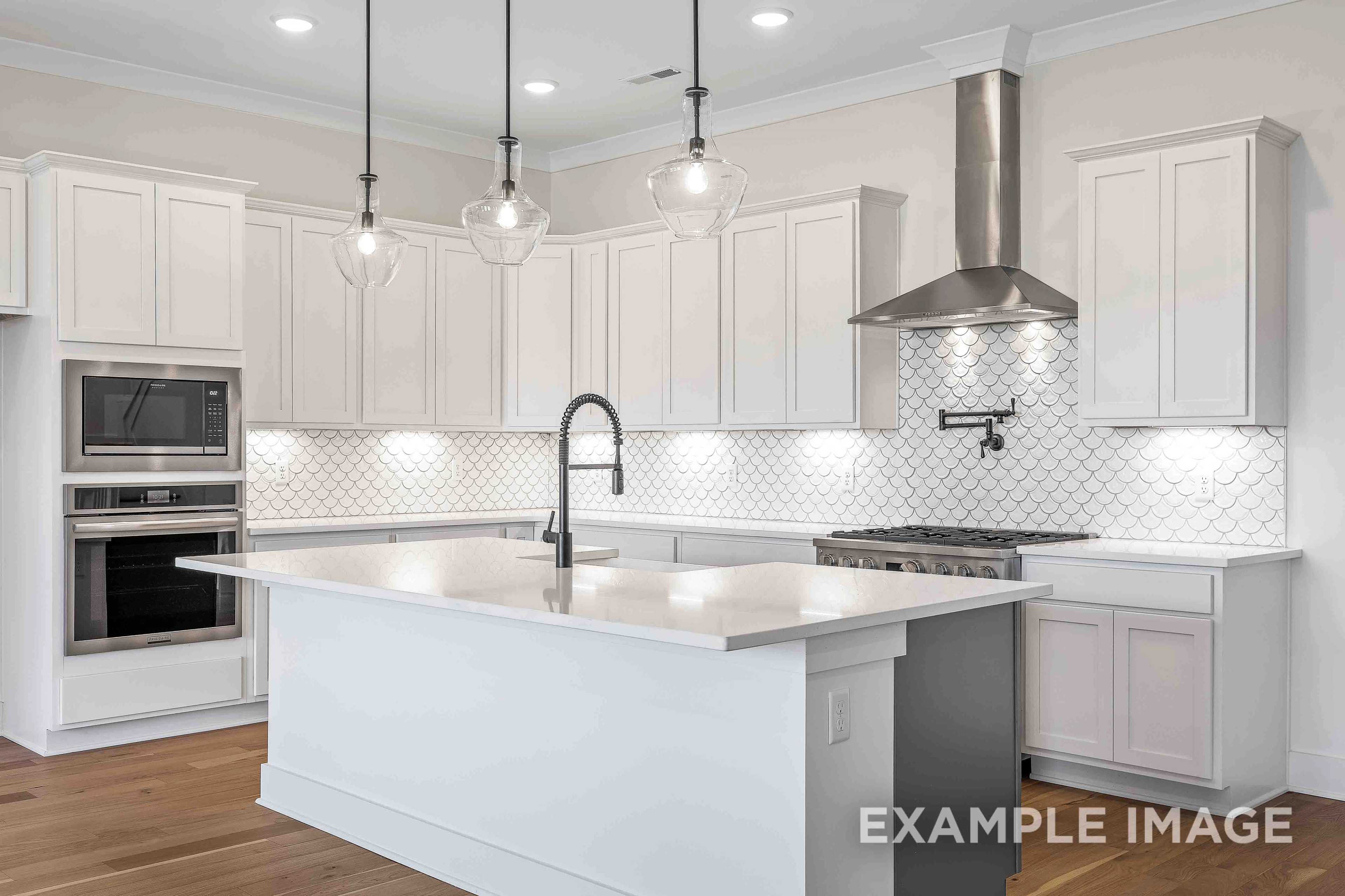 Spacious gourmet kitchen in The Albany A featuring white shaker cabinets, large island with farmhouse sink, stainless steel range, and subway tile backsplash