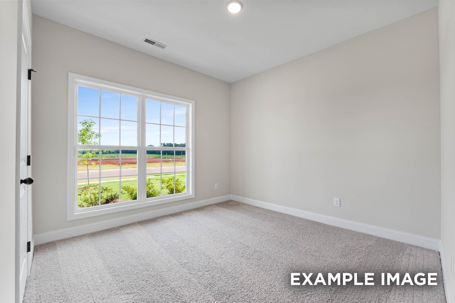 Bright, carpeted bedroom with large windows in The Franklin E floor plan at Bailey Park, Fayetteville, Tennessee.