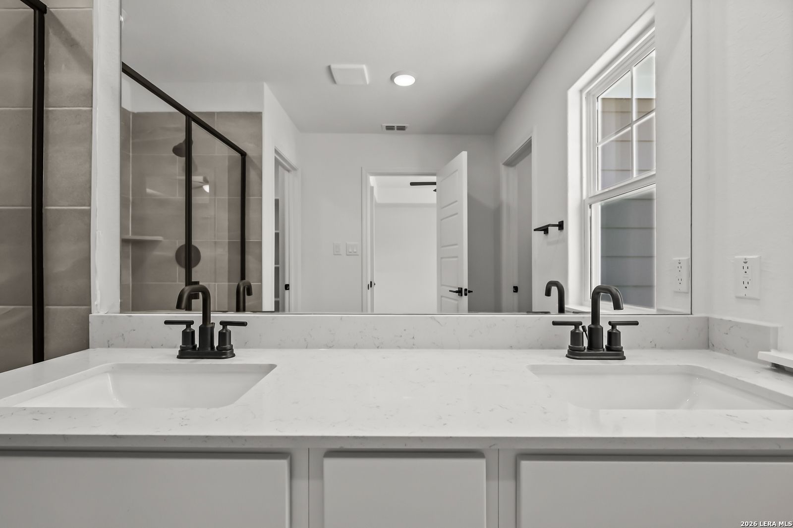 Modern double vanity with white quartz countertops and black fixtures in The Florence B home at Meadows at Oak Creek.