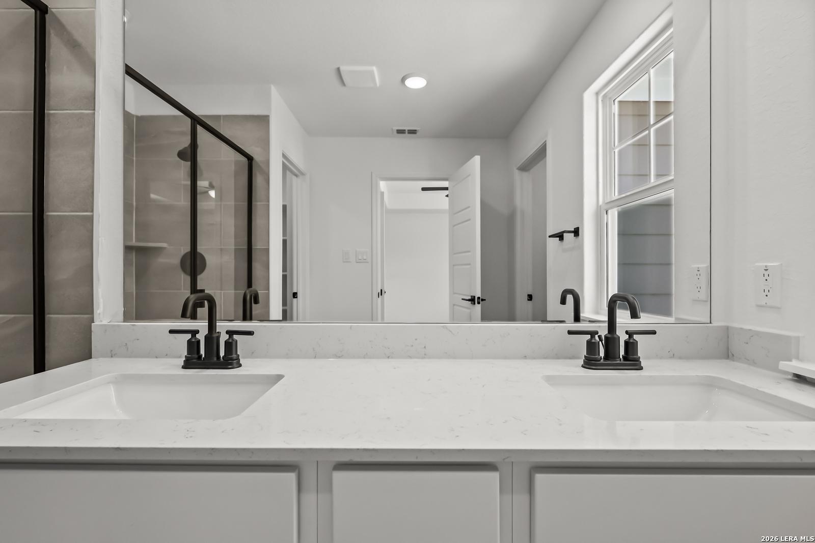 Modern double vanity with white quartz countertops and black fixtures in The Florence B home at Meadows at Oak Creek.