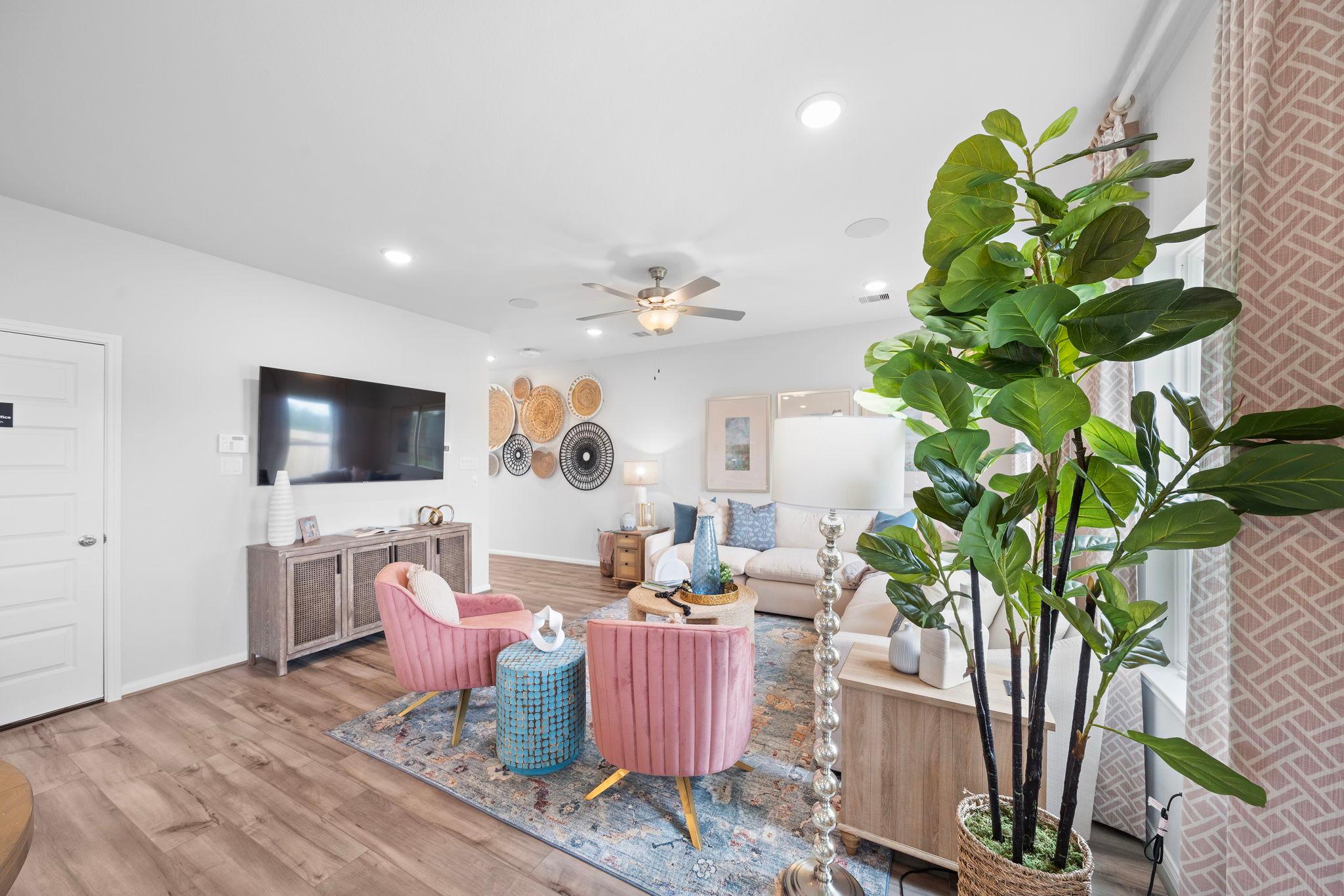 Spacious modern living room at Hill & Dale Ranch in Splendora Texas with pink velvet chairs, hardwood floors, potted plants