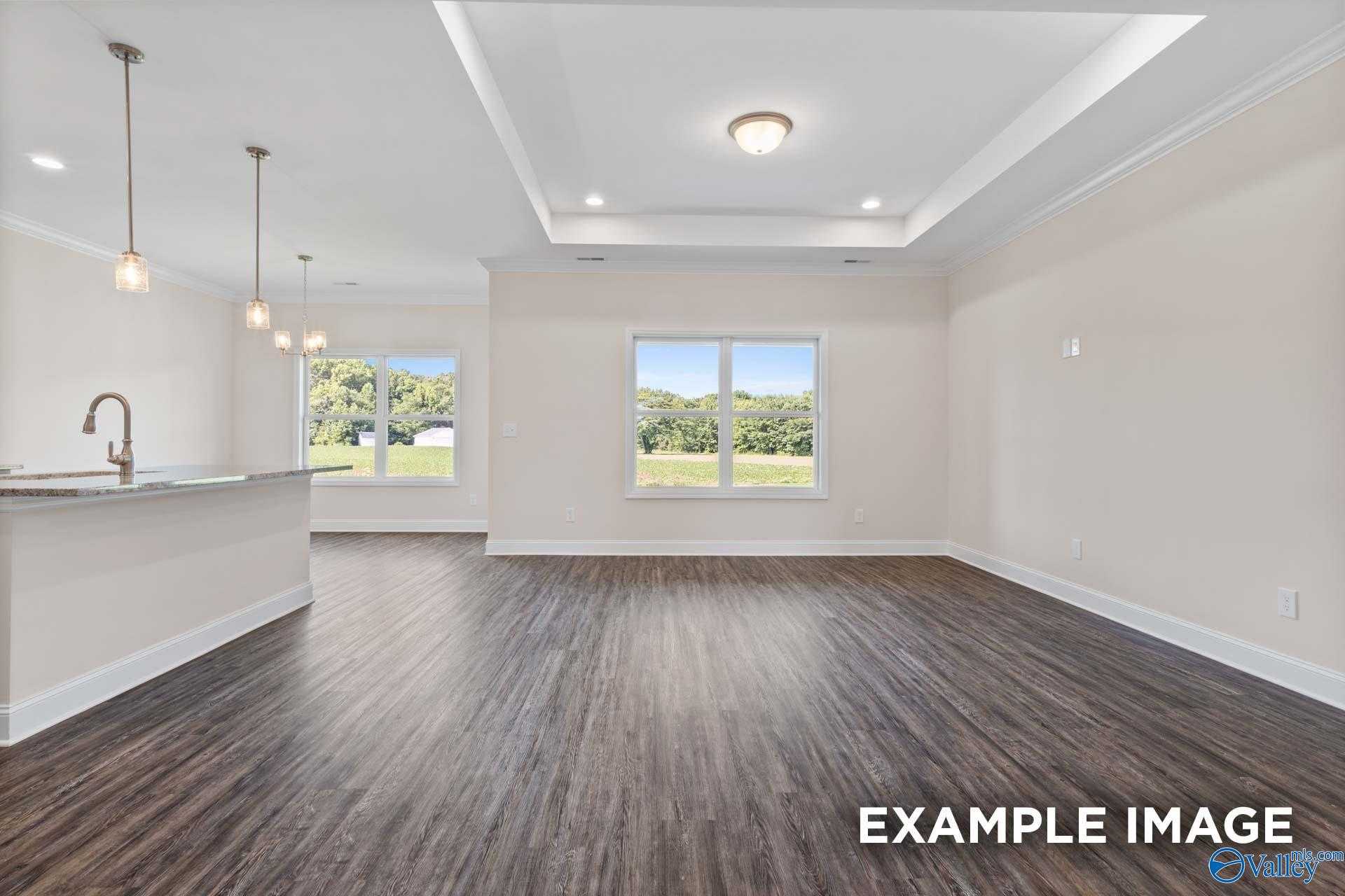 Open-concept kitchen and living area with hardwood floors, pendant lights, and wooded views in The Asheville by Davidson Homes, Arab, AL