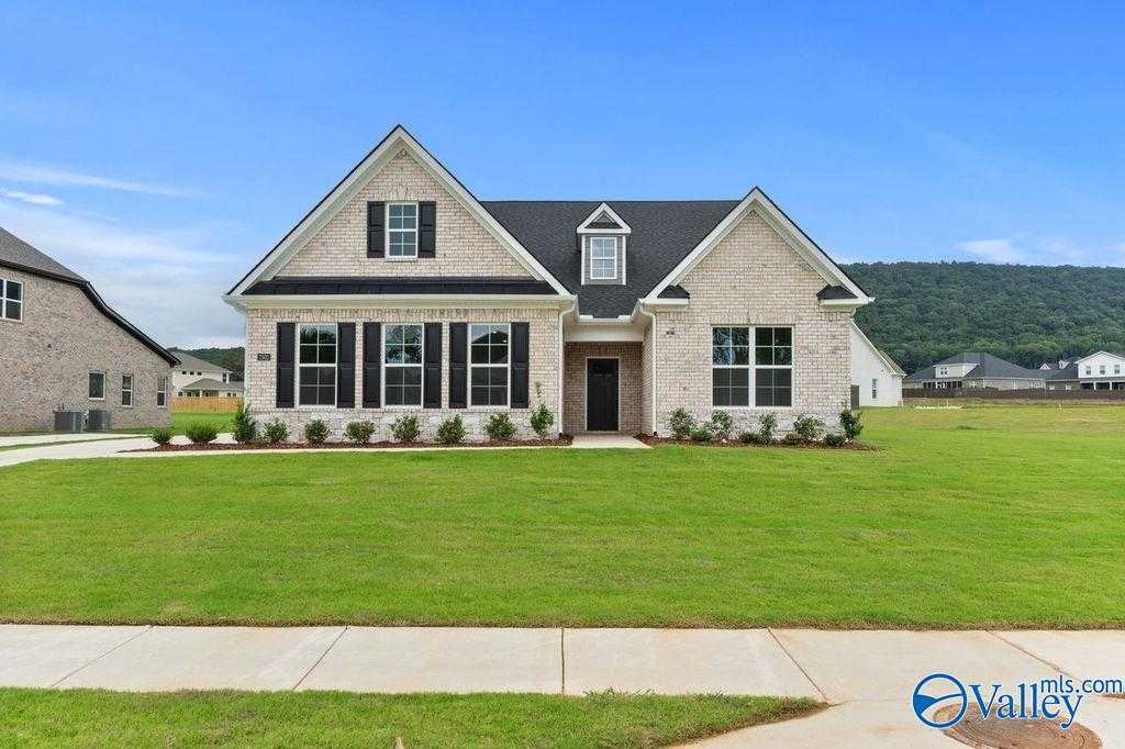 Charming 1.5-story brick home with gabled roof, black shutters, and lush green lawn in The Meadows at Hampton Cove, Owens Cross Roads, Alabama