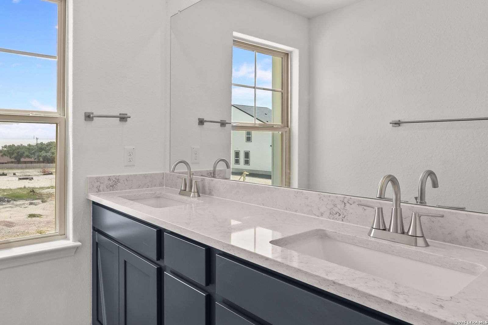 Modern double vanity with quartz countertops and navy cabinets in The Gillian C home at Meadows at Oak Creek, San Antonio.