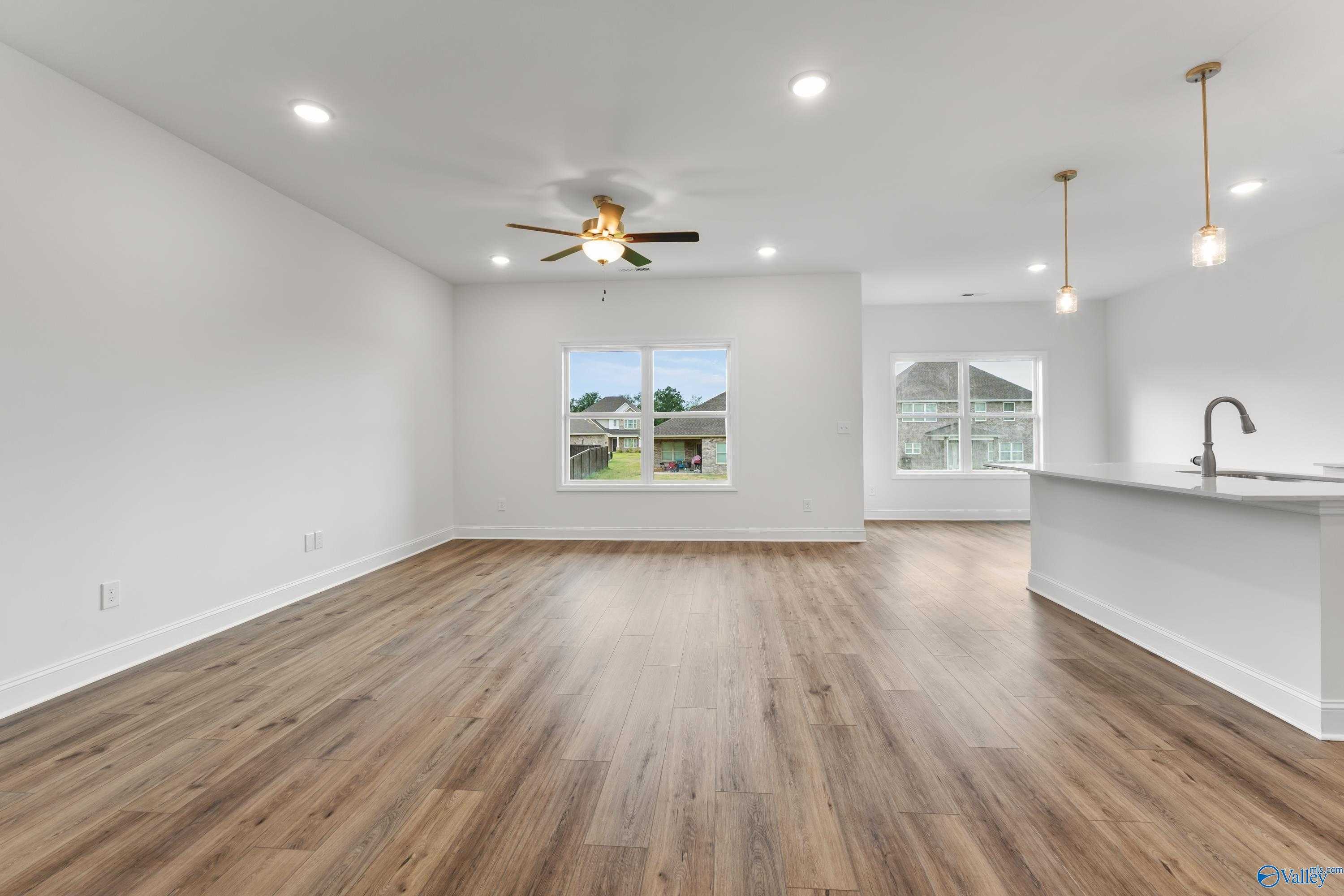 Open living and kitchen area with white island, large windows, hardwood floors in Davidson Homes The Asheville C, New Market, AL
