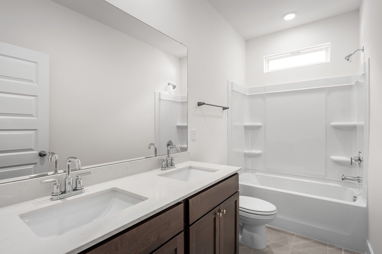 Modern bathroom with dual vanity, white countertops, and tub-shower combo in The Cottonwood E, Woods Crossing, Gallatin, TN.
