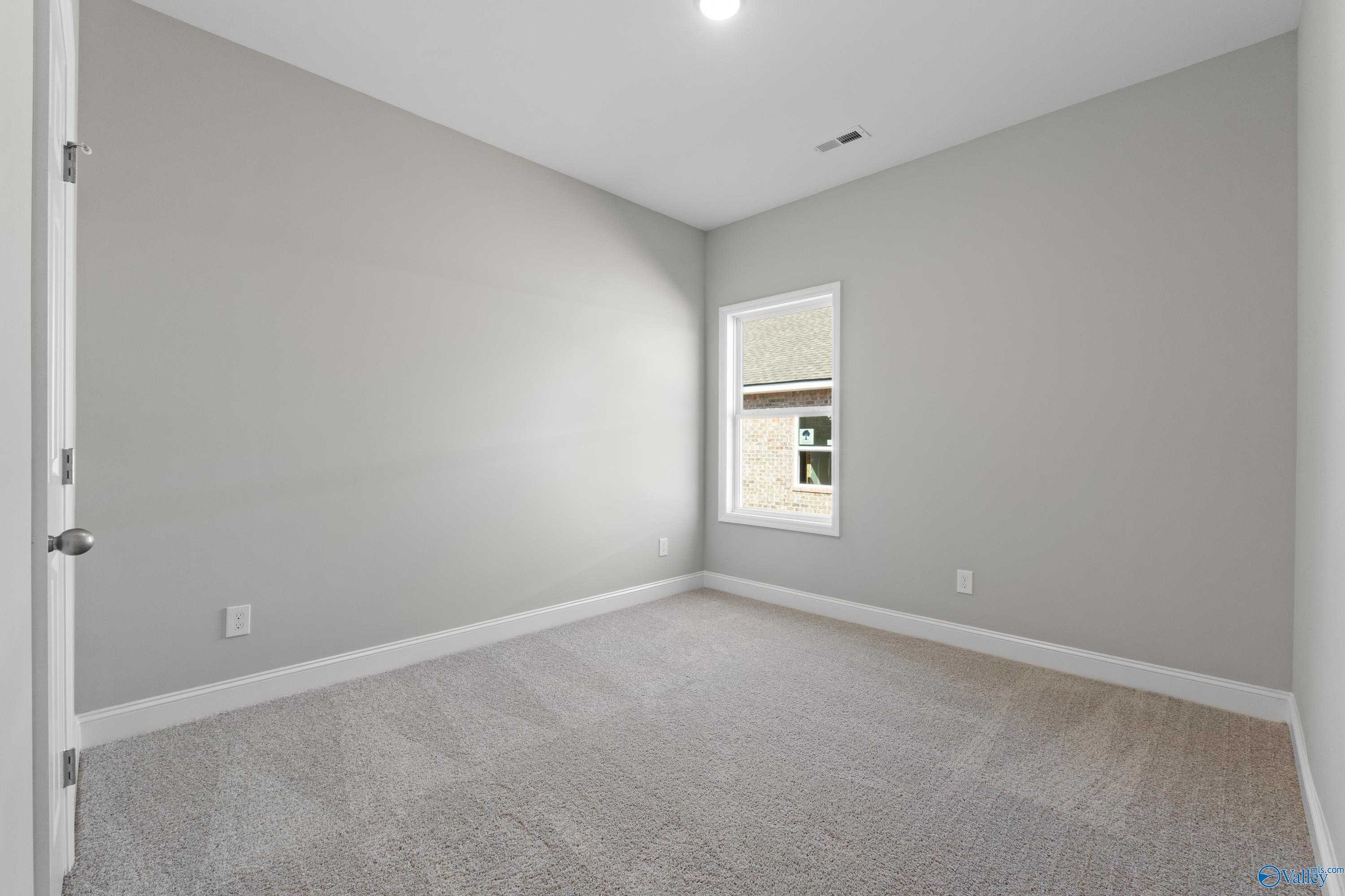 Bright secondary bedroom featuring gray walls, neutral carpet, and window in Davidson Homes The Asheville C, Athens, Alabama