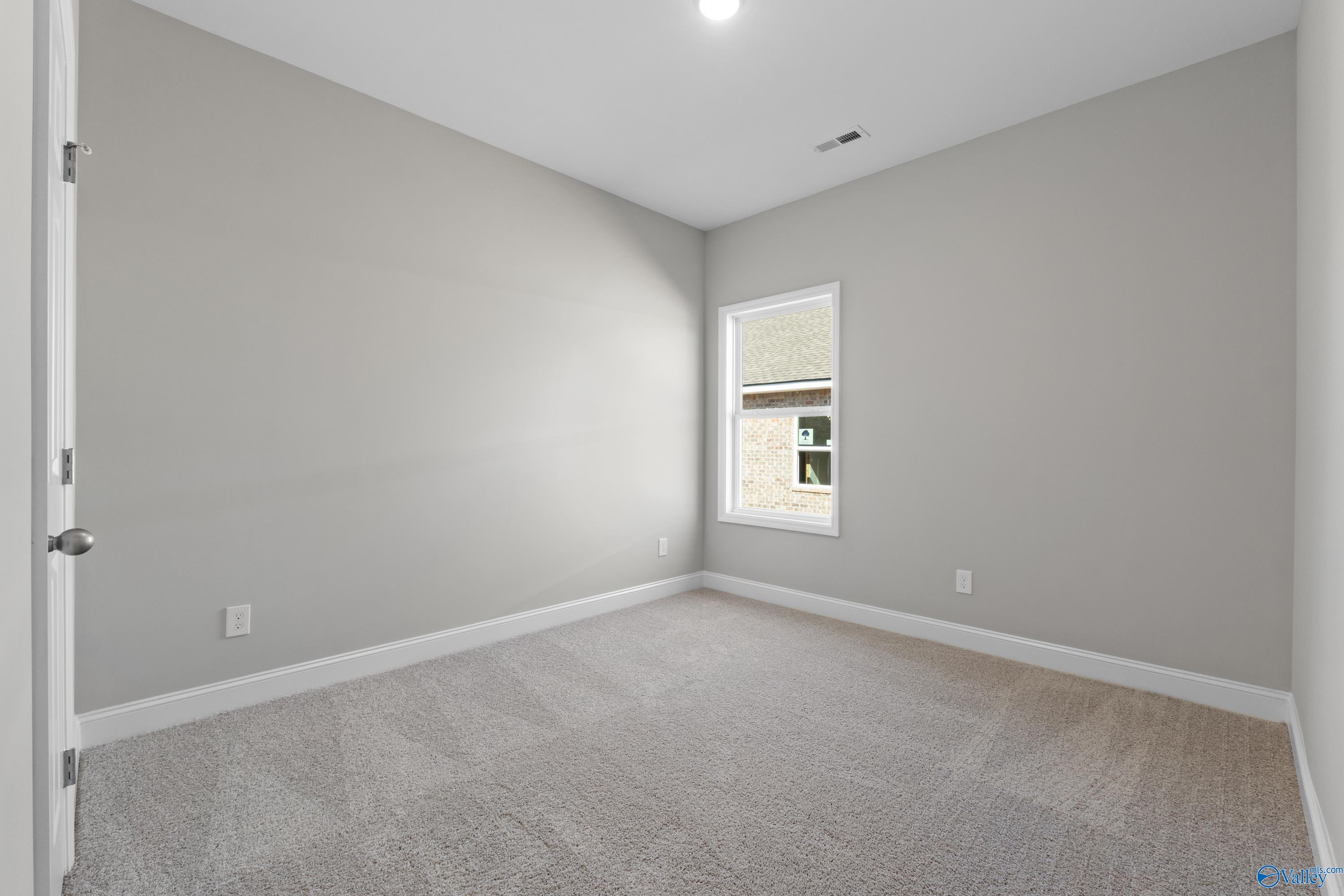 Bright secondary bedroom featuring gray walls, neutral carpet, and window in Davidson Homes The Asheville C, Athens, Alabama
