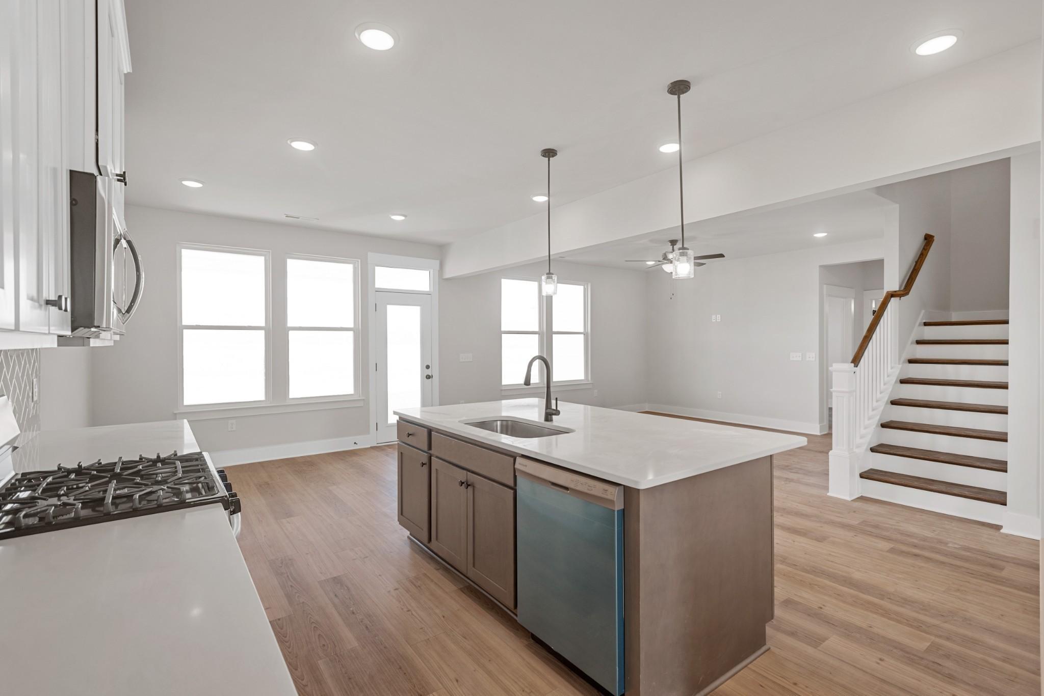 Bright open-concept kitchen with white shaker cabinets, quartz island sink, gas range, and hardwood floors in Davidson Homes Willow B, White House, TN