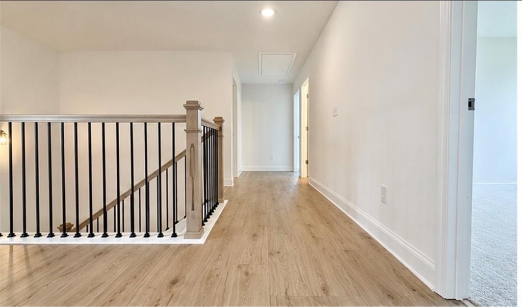 Bright second-floor landing with wood-style flooring and metal balusters in Davidson Homes Hickory C, Wehunt Meadows.