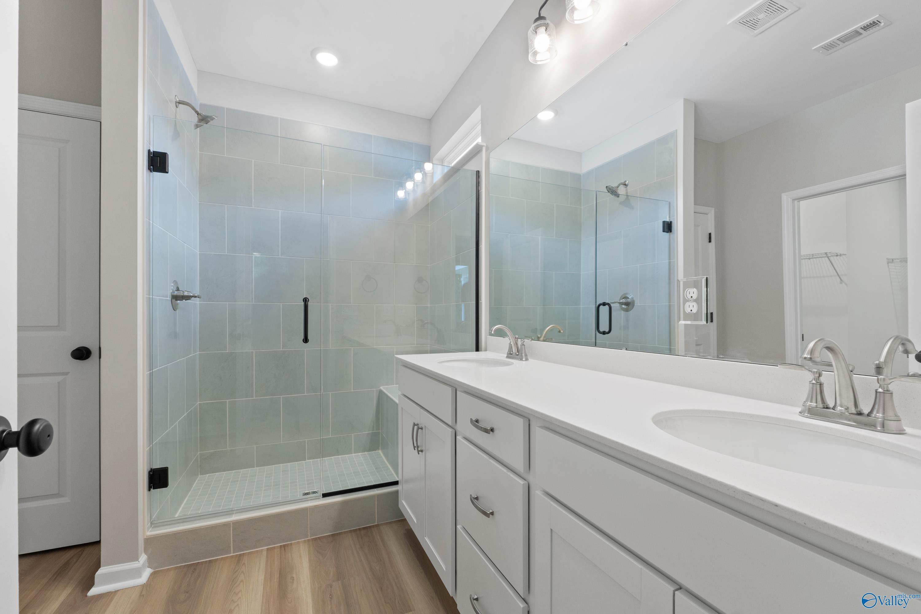 Modern master bathroom with frameless glass shower and double white vanity in Davidson Homes The Phoenix, Fayetteville, TN