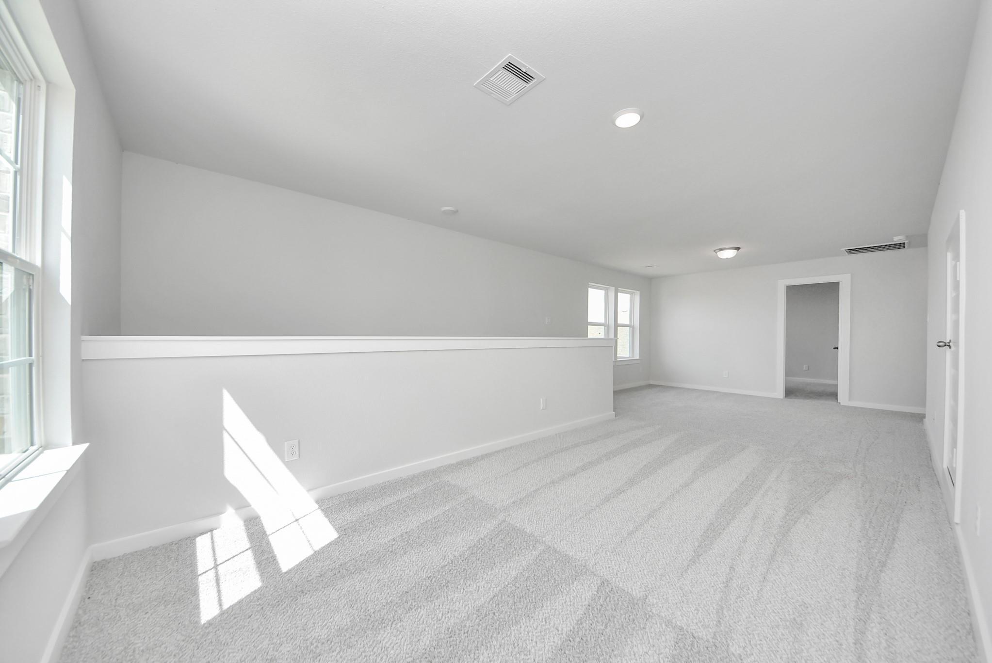 Spacious carpeted game room in The Verano B floor plan by Davidson Homes in Sunterra, Katy, Texas.