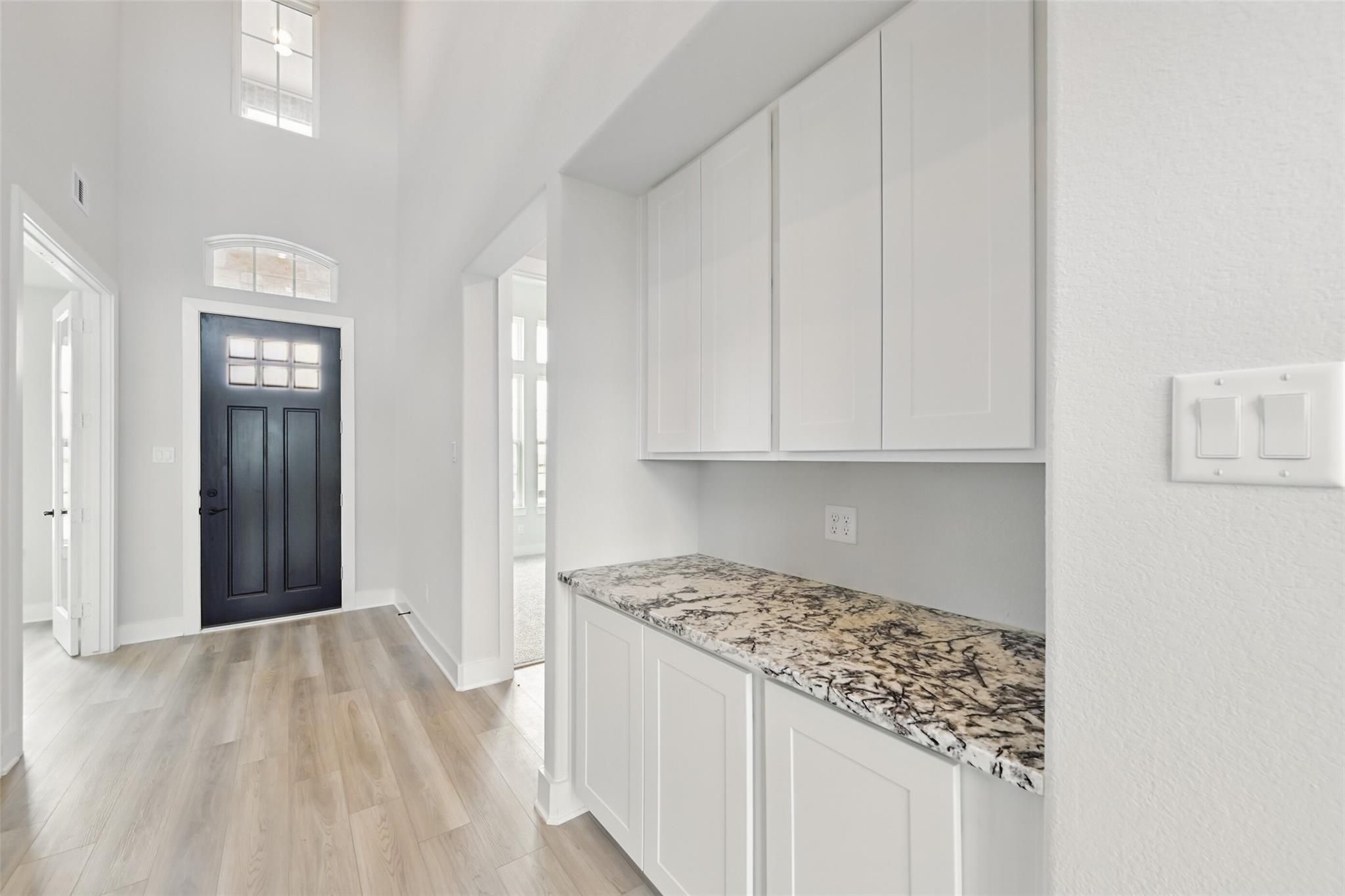 Grand entry foyer with black front door, arched hallway to white kitchen cabinets and granite counters in Davidson Homes The Victoria C, Lago Mar