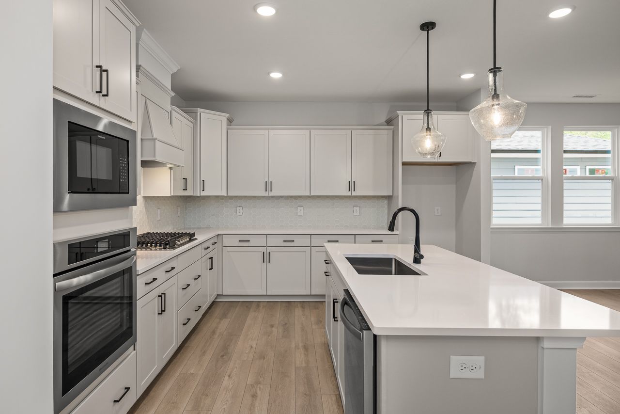 Modern kitchen in The Birch II featuring white cabinetry, quartz countertops, a large center island, and stainless appliances.