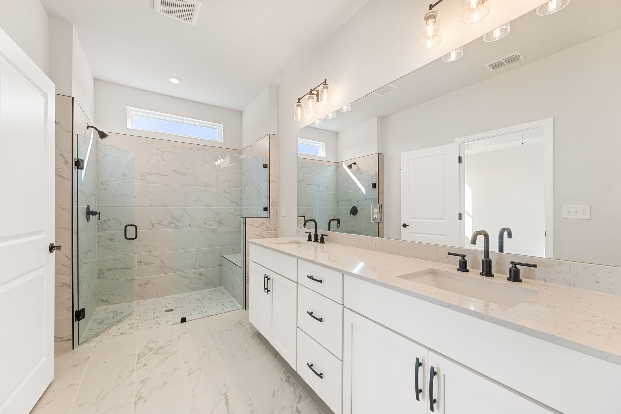 Modern master bathroom with double quartz vanity, frameless glass shower, marble tiles in Davidson Homes The Glenwood C, Loganville, GA