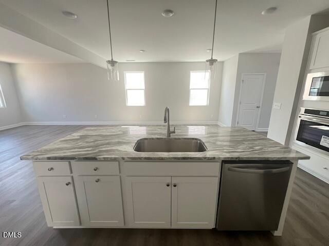 Modern kitchen island with gray veined quartz countertop, deep sink, white cabinets, stainless dishwasher and oven in Davidson Homes Adalynn A, Lillington NC