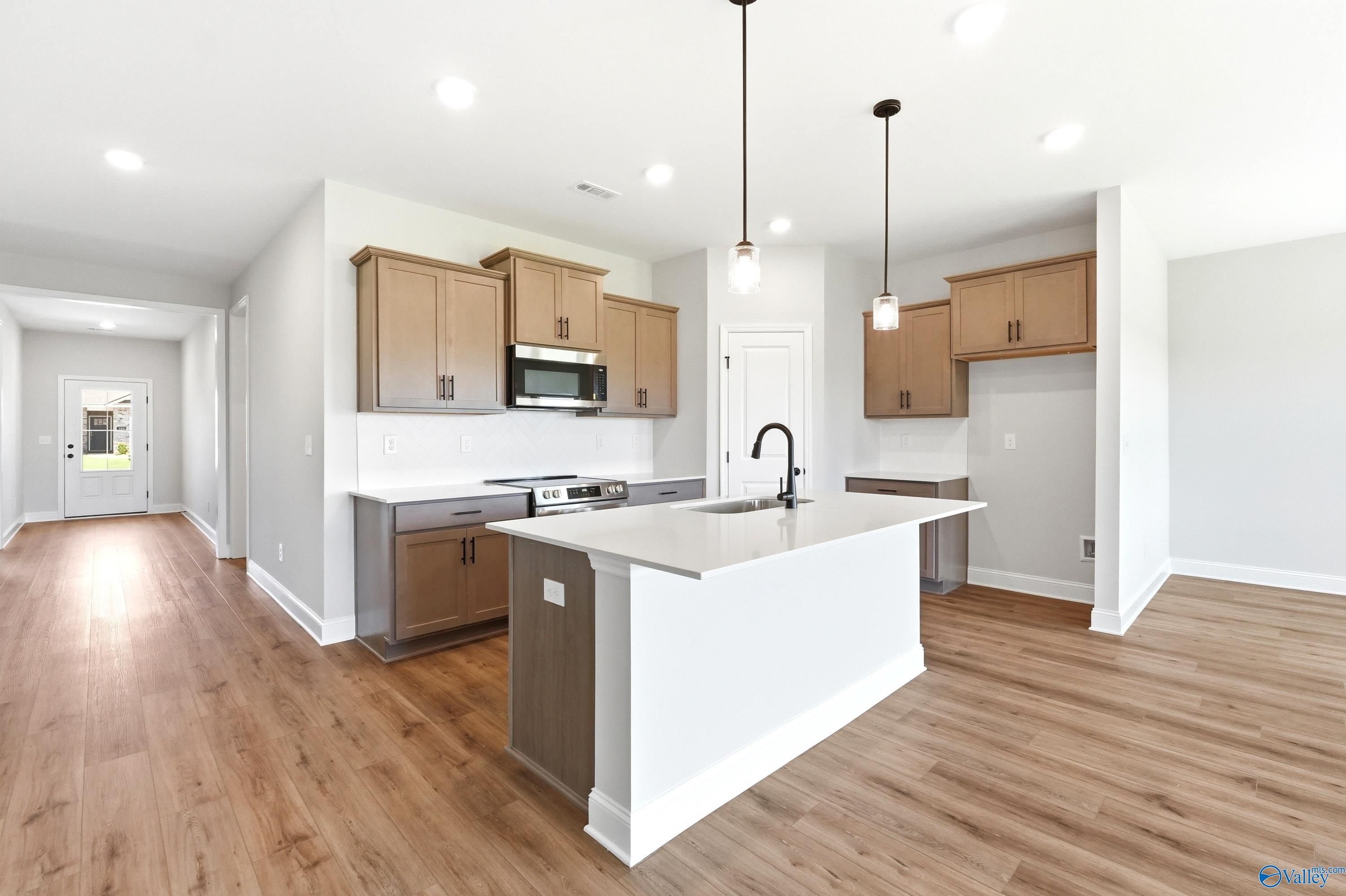 Modern kitchen with island, wood cabinets, and quartz countertops in The Daphne floor plan, Clearview, Hazel Green, AL.