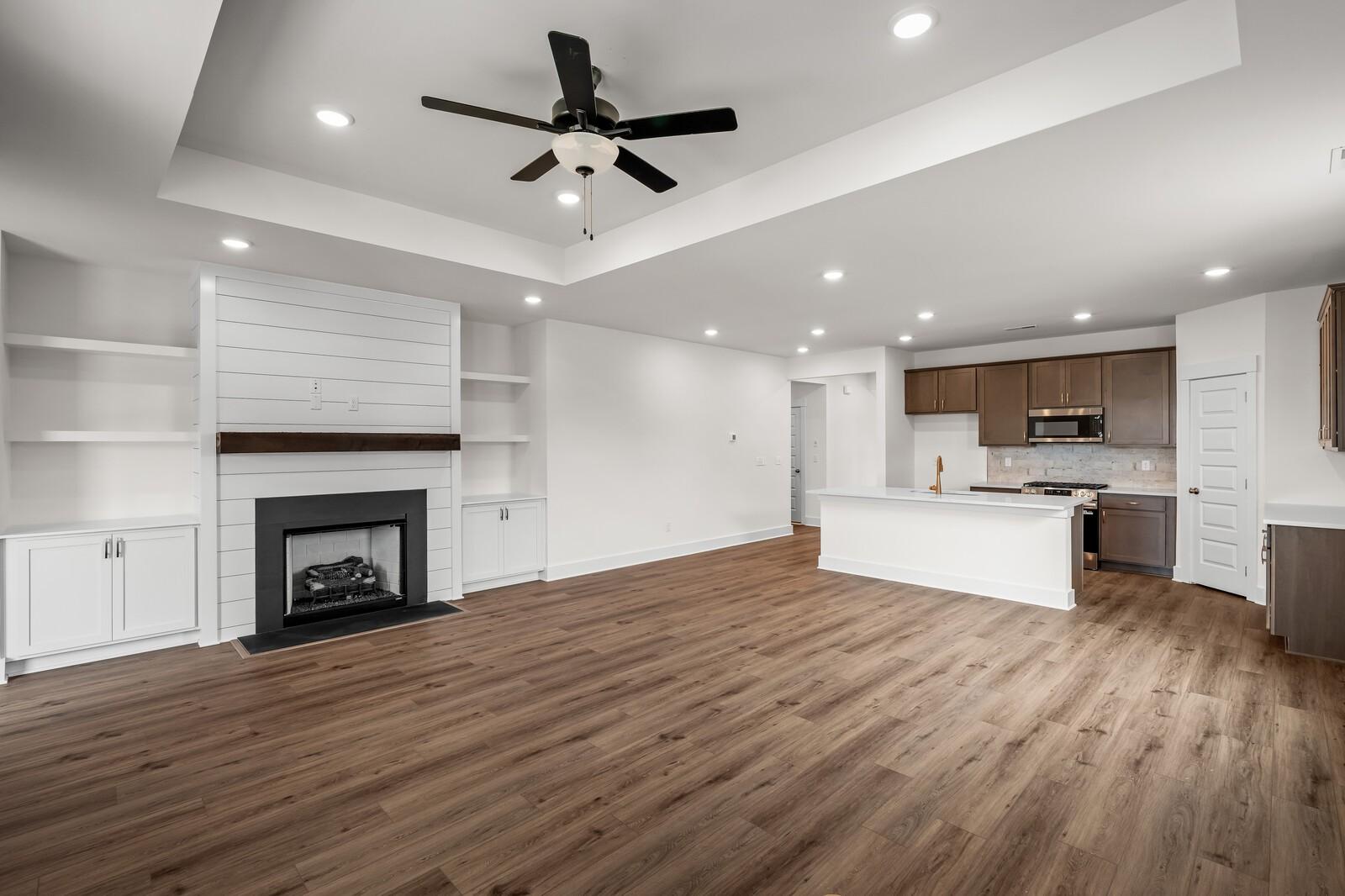 Open-concept living room with fireplace and modern kitchen in The Prairie C floor plan at Woods Crossing, Gallatin, TN.