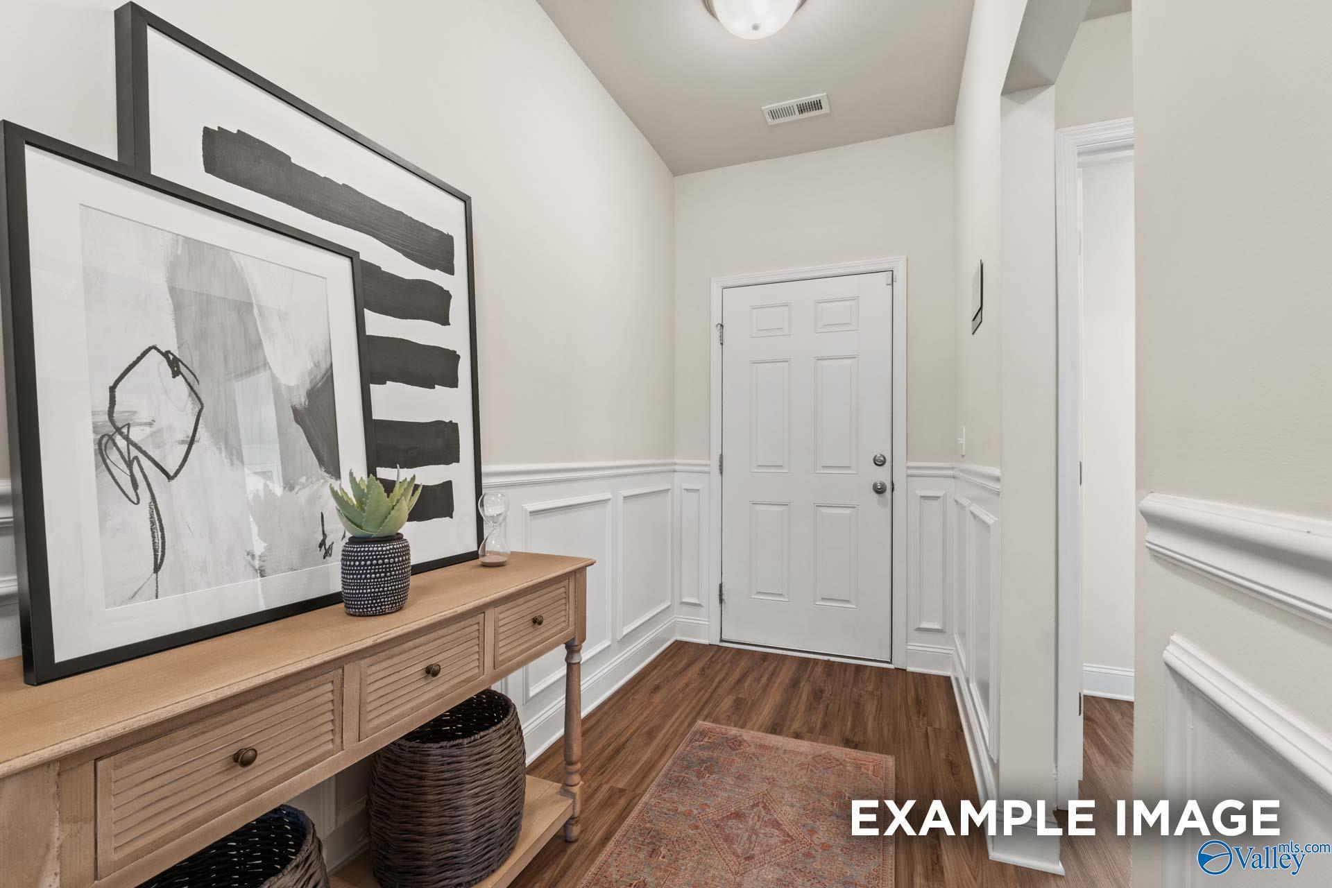 Elegant hallway with wainscoting, abstract black-and-white art, wooden console table and plant in Davidson Homes The Franklin C, New Market, Alabama