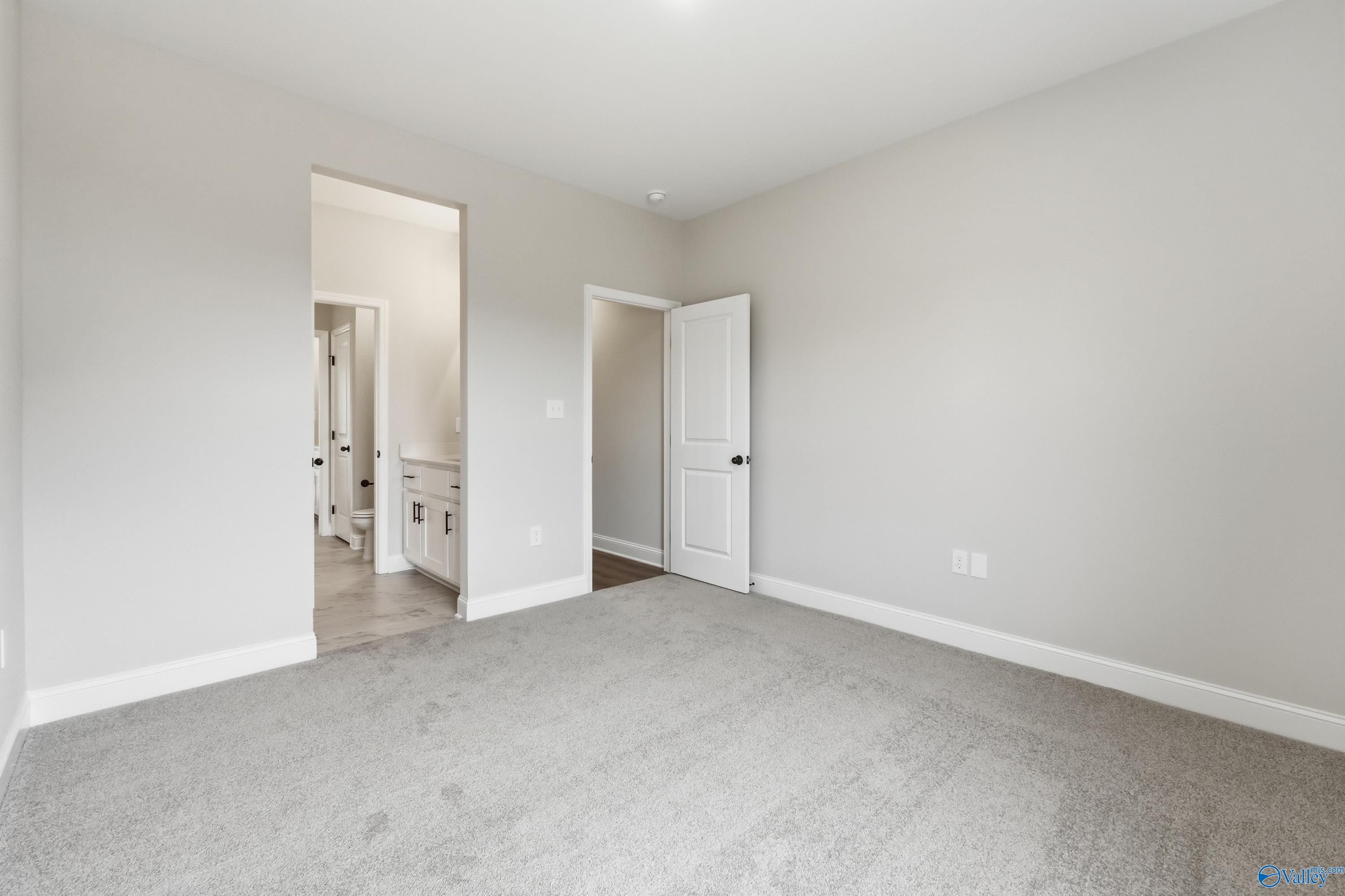 Spacious master bedroom with gray walls, carpet flooring, and en-suite bath in Davidson Homes The Finleigh, Meridianville, Alabama