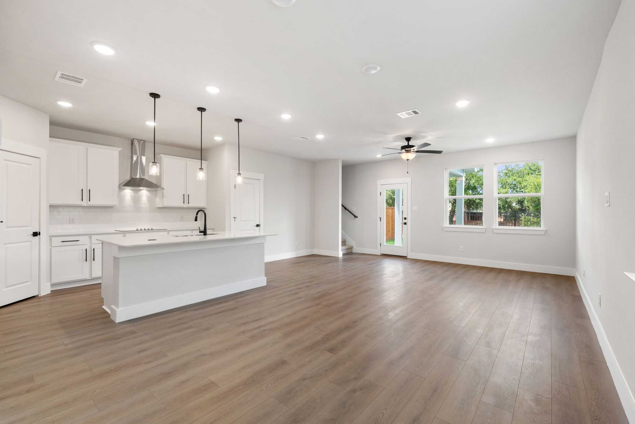Modern open-concept kitchen with white island, stainless appliances, hardwood floors in Davidson Homes The Durham E, Wylie TX