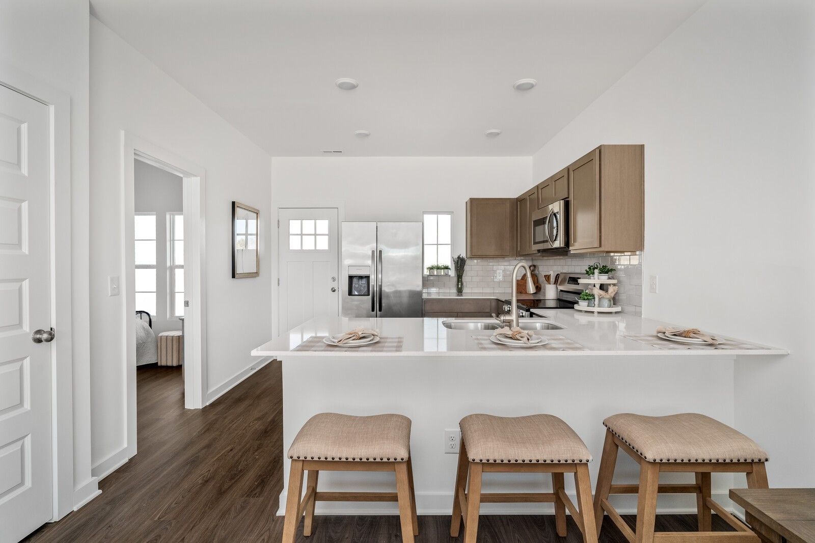 Modern open-concept kitchen with stainless steel appliances, beige cabinets, and bar island in Davidson Homes Cumberland A, Gallatin, TN