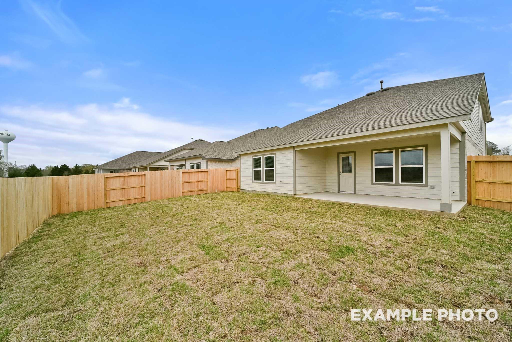Covered back patio with sliding doors and windows overlooking fenced grassy backyard in Davidson Homes The Tierra B, Beasley, Texas