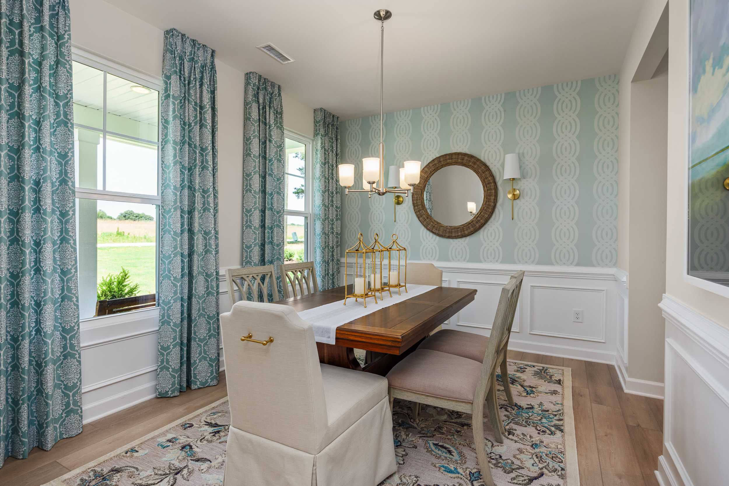 Elegant dining room at Retreat at North Main in Lillington NC with wooden table, chandelier, round mirror, and patterned wallpaper