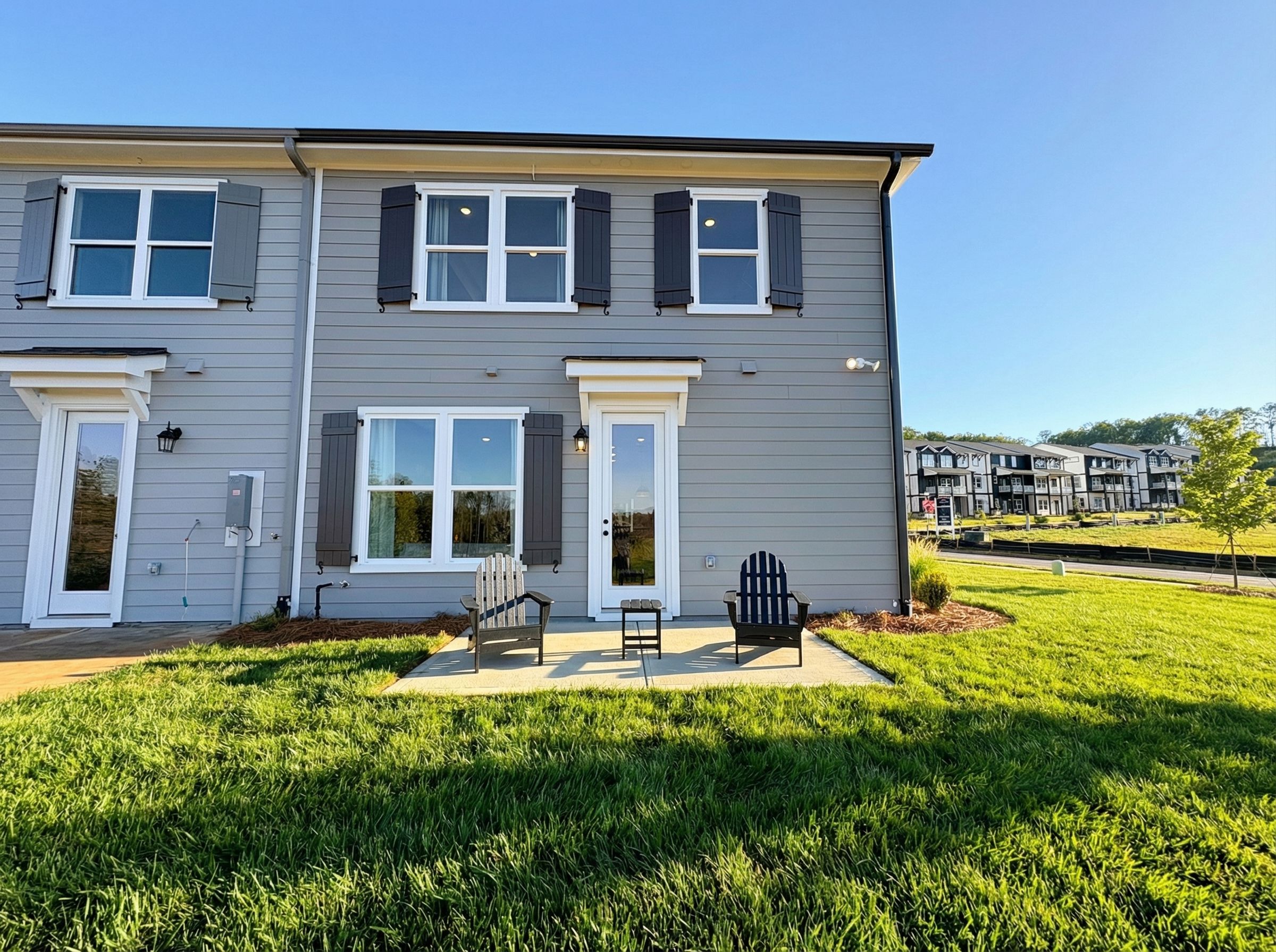 Gray townhome exterior at Hemingway in Cumming, Georgia with patio, Adirondack chairs, and lush green lawn