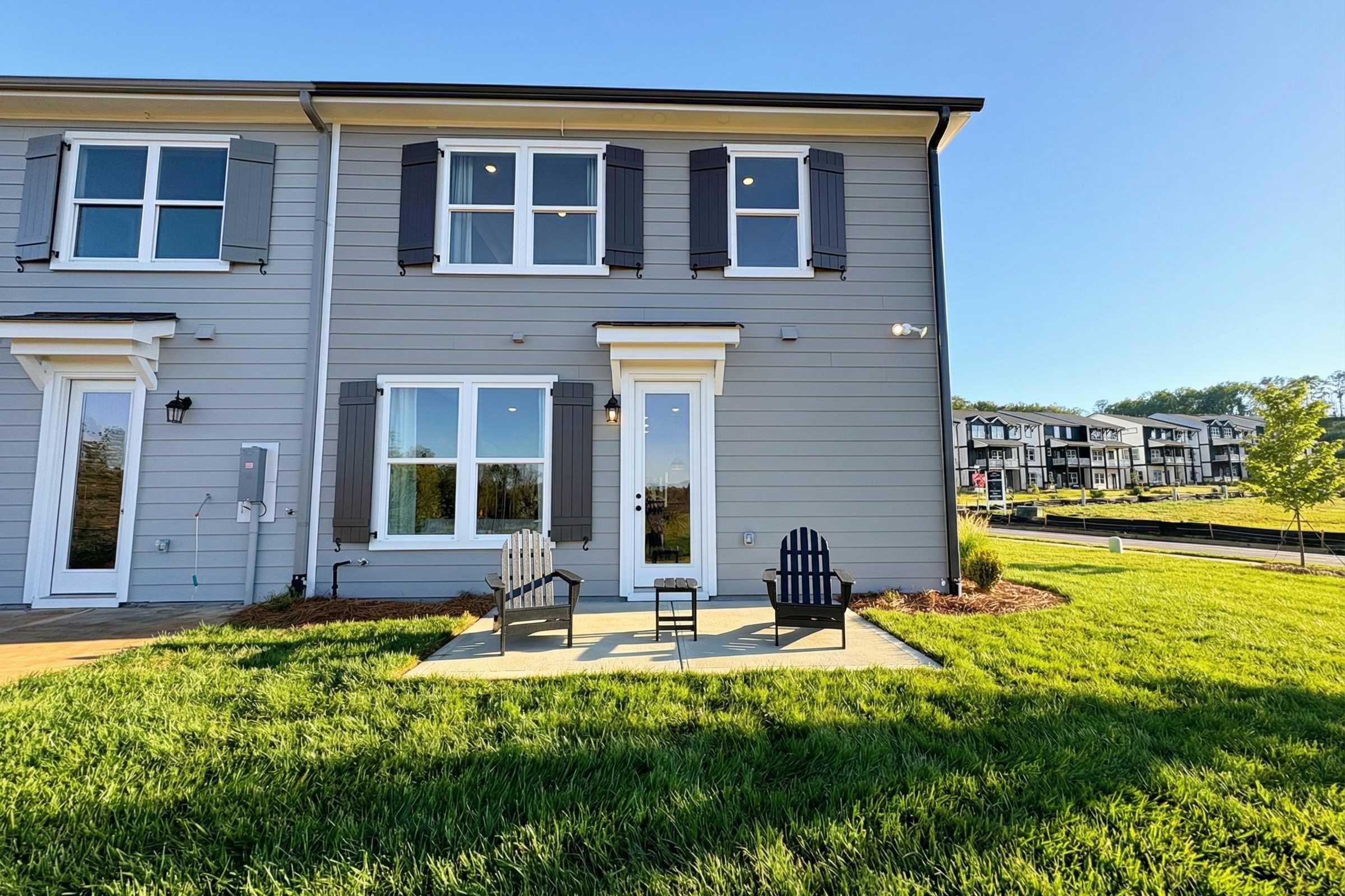 Gray townhome exterior at Hemingway in Cumming, Georgia with patio, Adirondack chairs, and lush green lawn