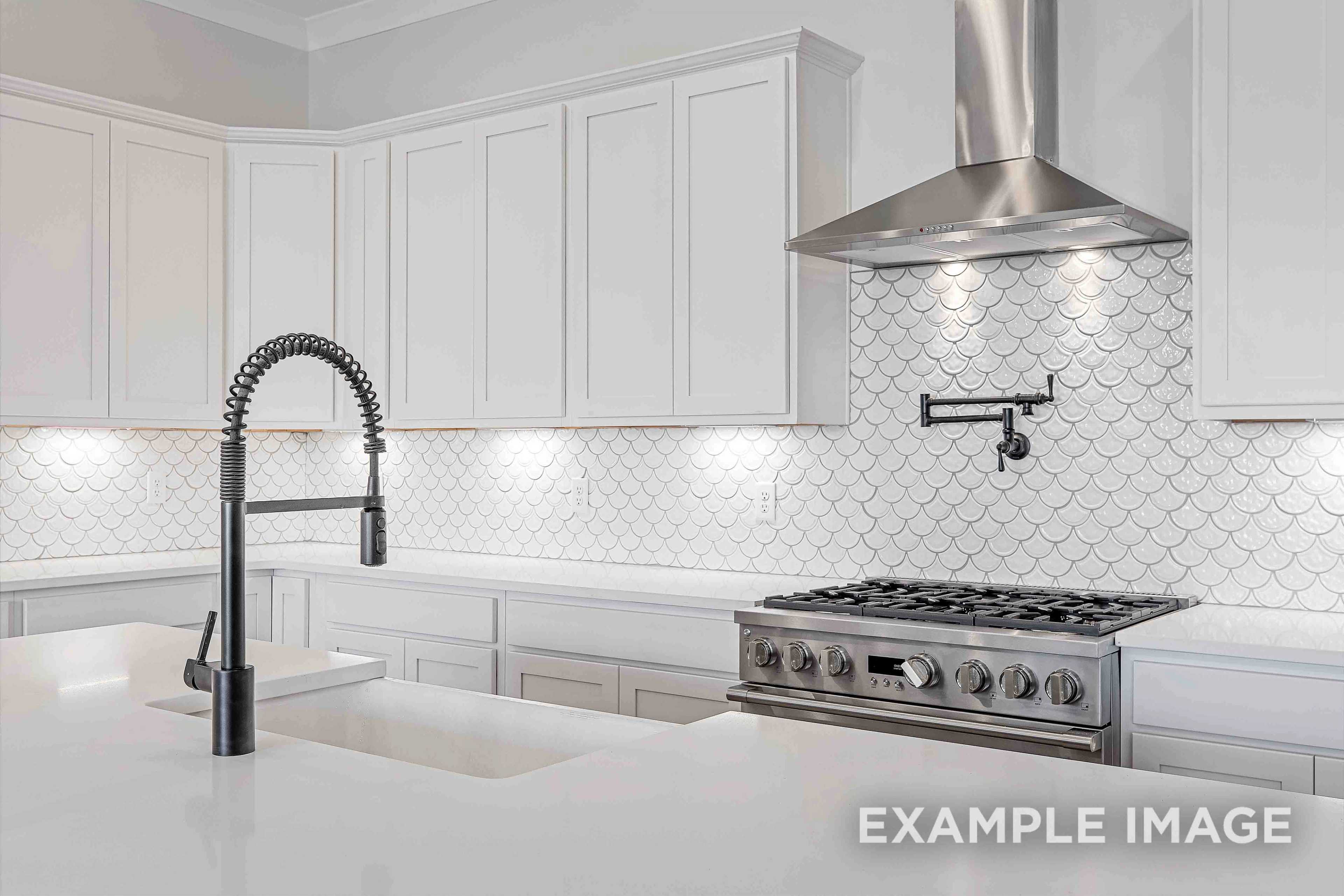 Modern kitchen in The Albany A by Davidson Homes: white shaker cabinets, scalloped tile backsplash, stainless steel range, pull-down faucet