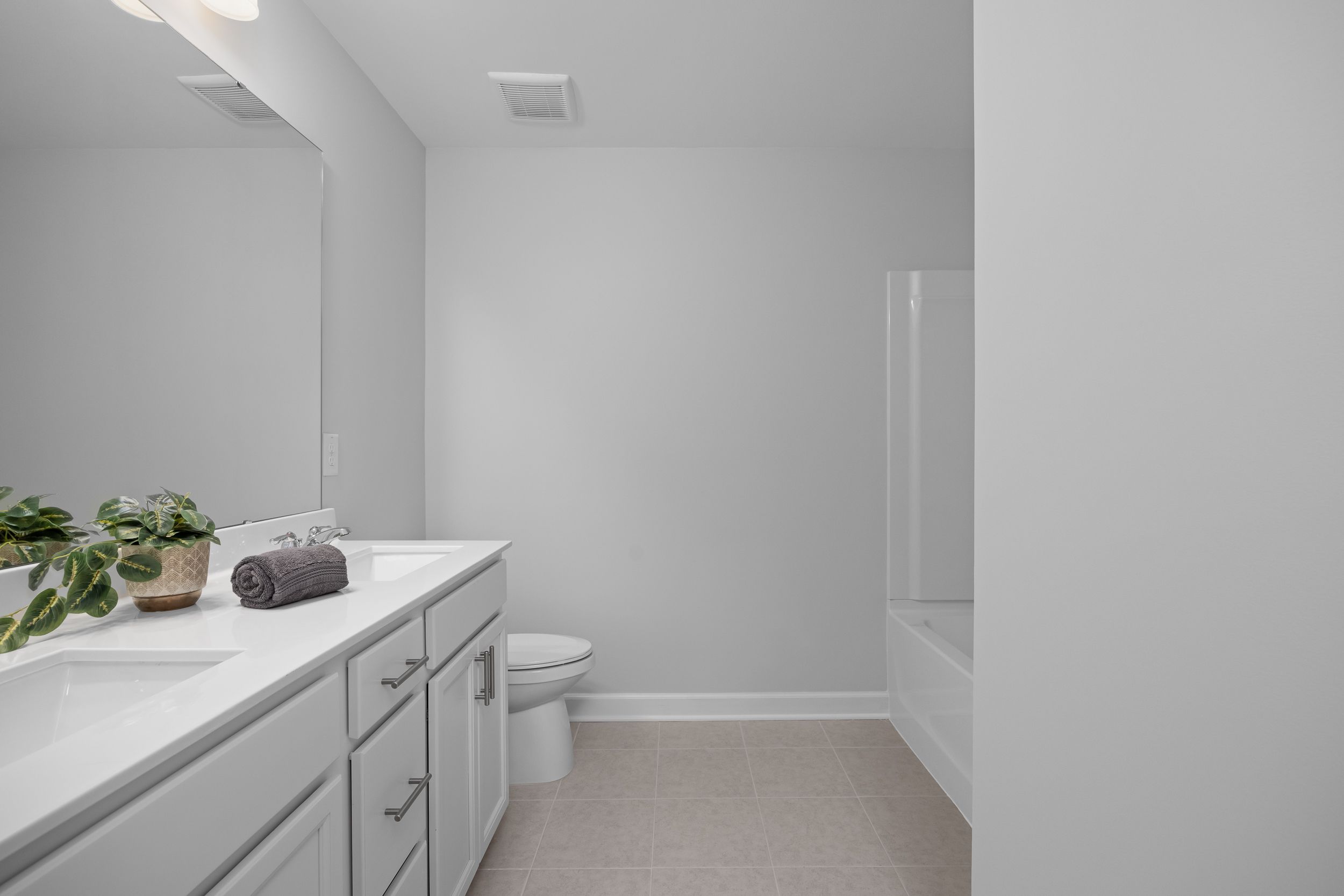 Modern bathroom in The Warren featuring a dual vanity, white cabinetry, and a tub-shower combo in Lillington, North Carolina.