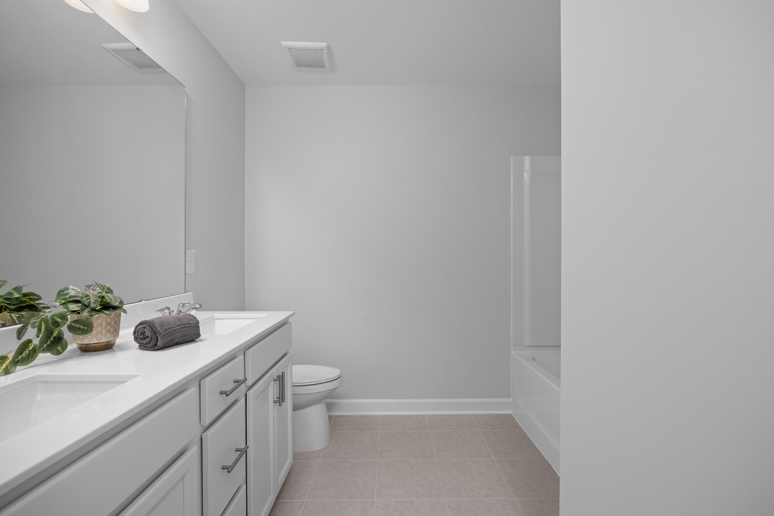 Modern bathroom in The Warren featuring a dual vanity, white cabinetry, and a tub-shower combo in Lillington, North Carolina.