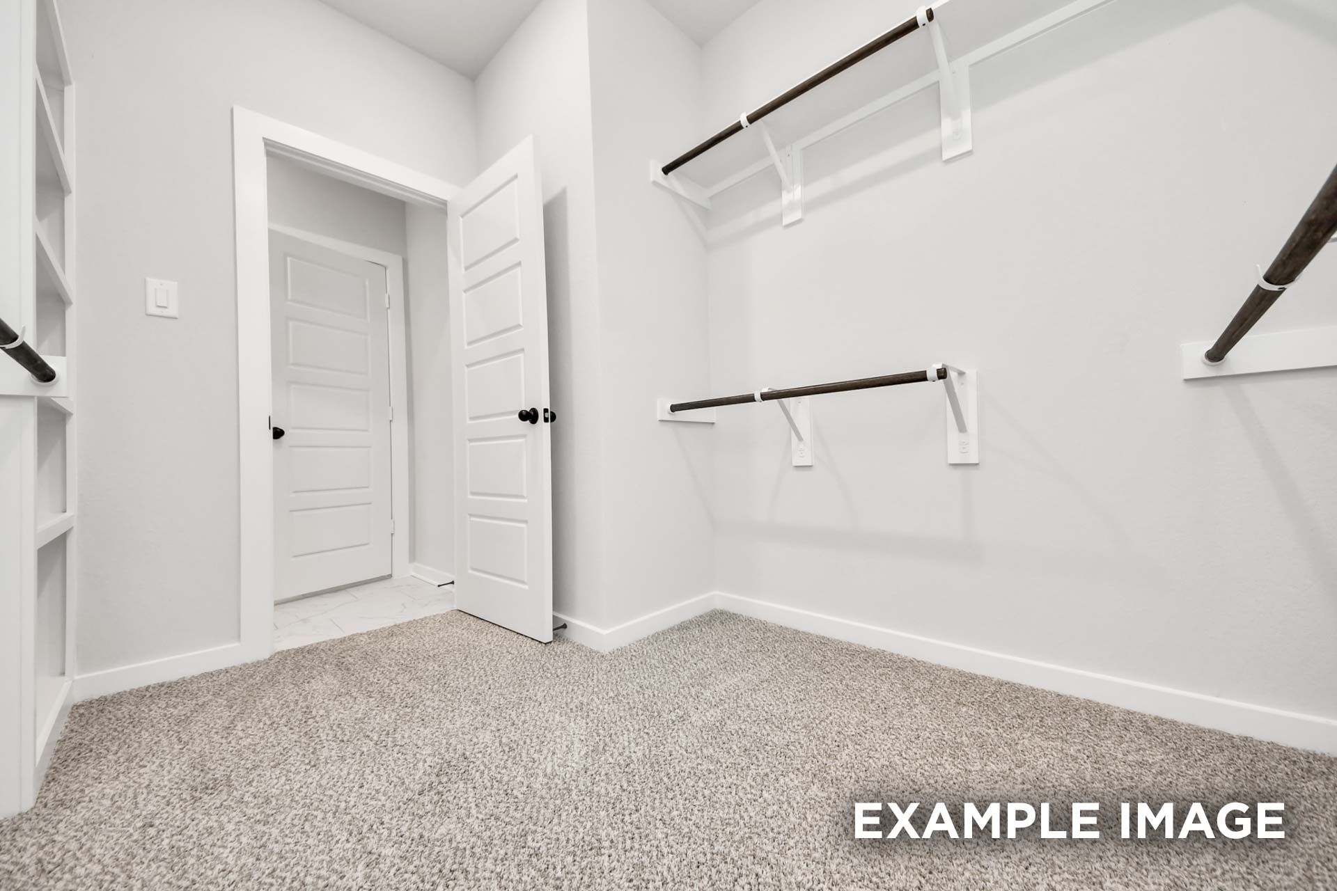 Spacious walk-in closet in The Sorrento master suite featuring custom shelving, hanging rods, and plush carpeting.