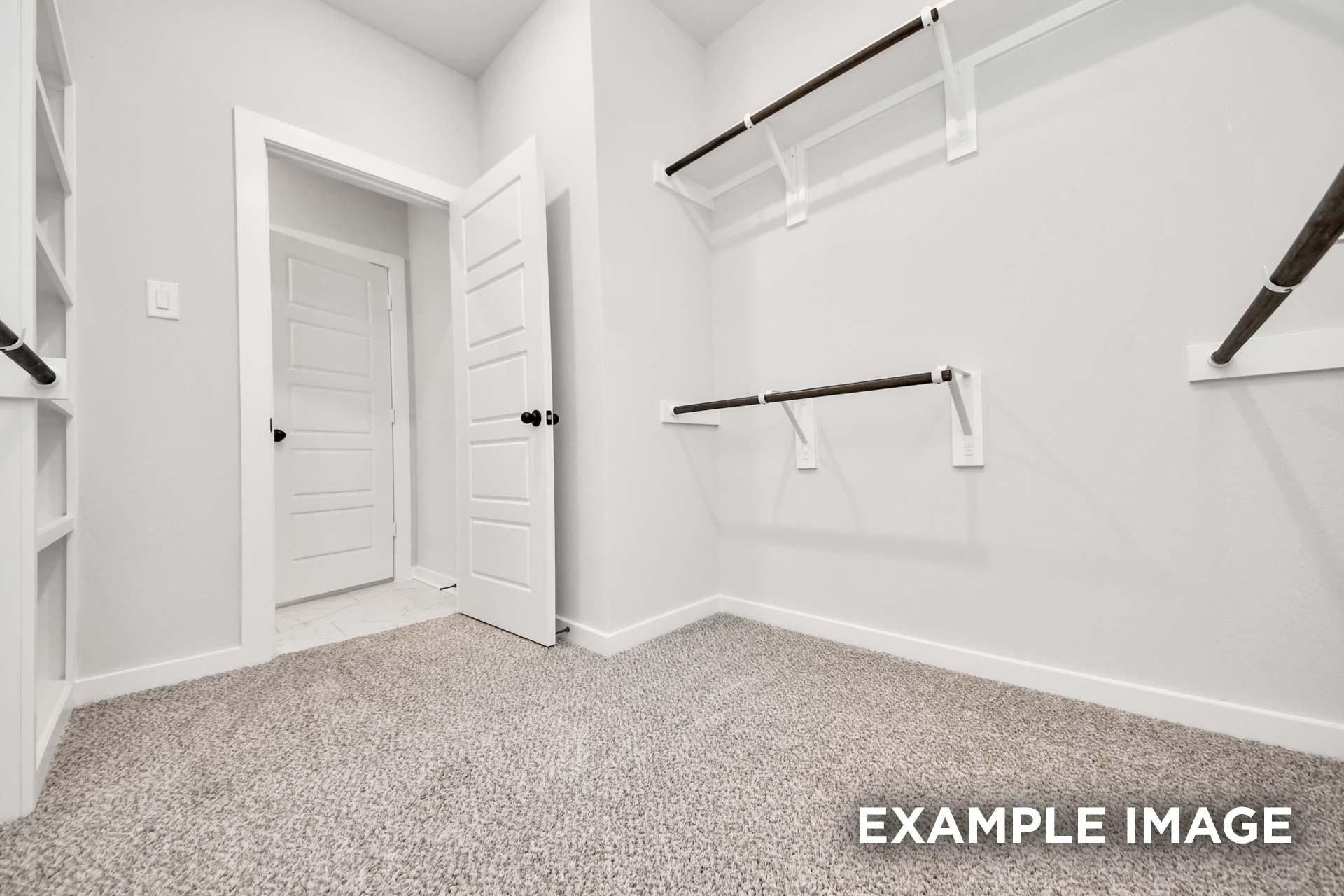 Spacious walk-in closet in The Sorrento master suite featuring custom shelving, hanging rods, and plush carpeting.